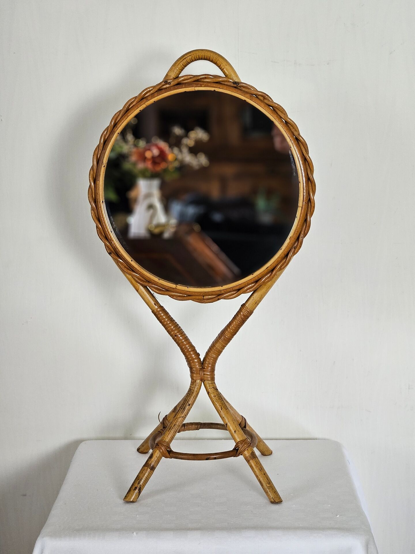 Vintage double-sided round mirror on a rattan stand.