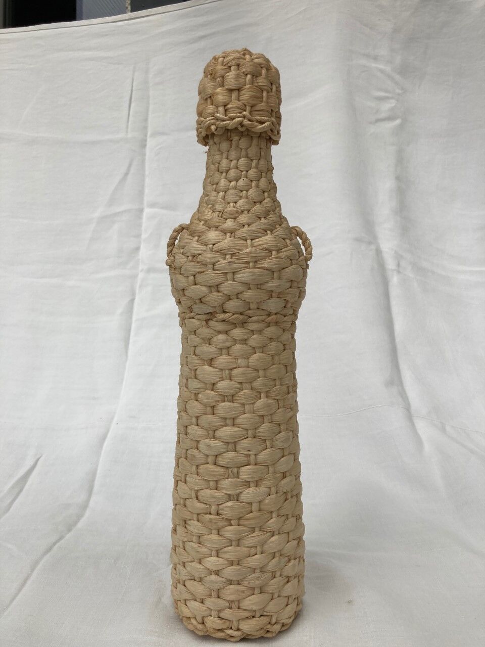 Bottle surrounded by wicker or raffia