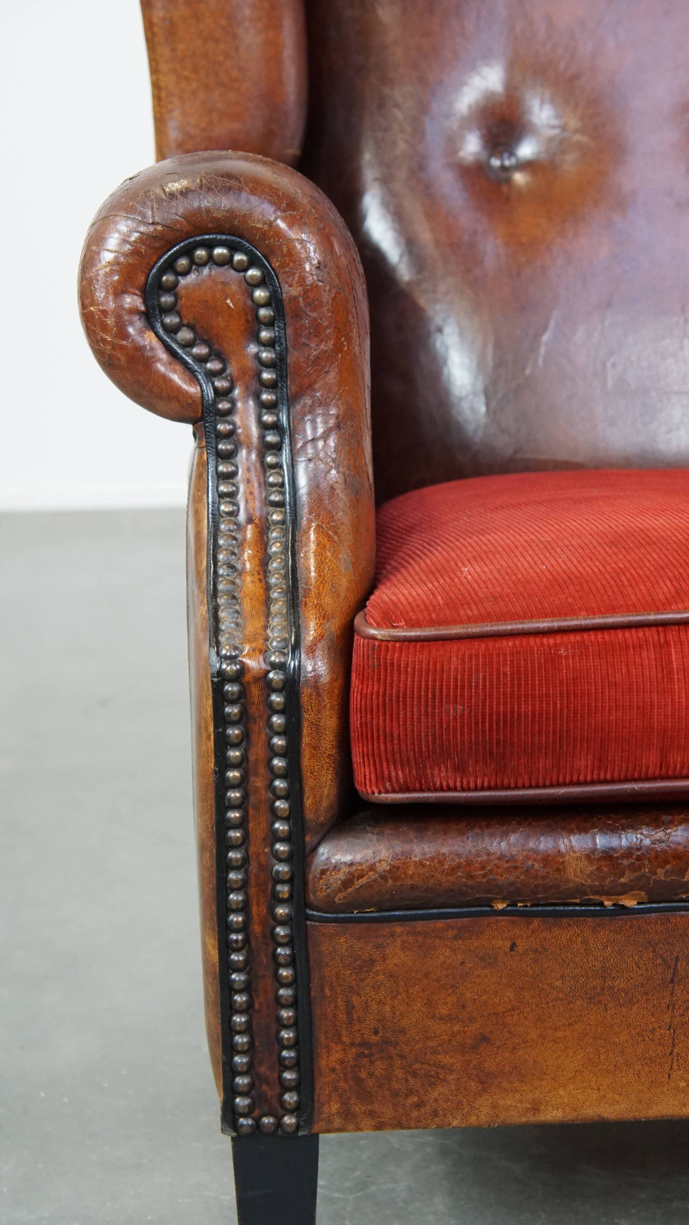 Sheepskin leather wingback chair with a red corduroy seat cushion