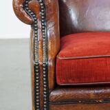 Sheepskin leather wingback chair with a red corduroy seat cushion