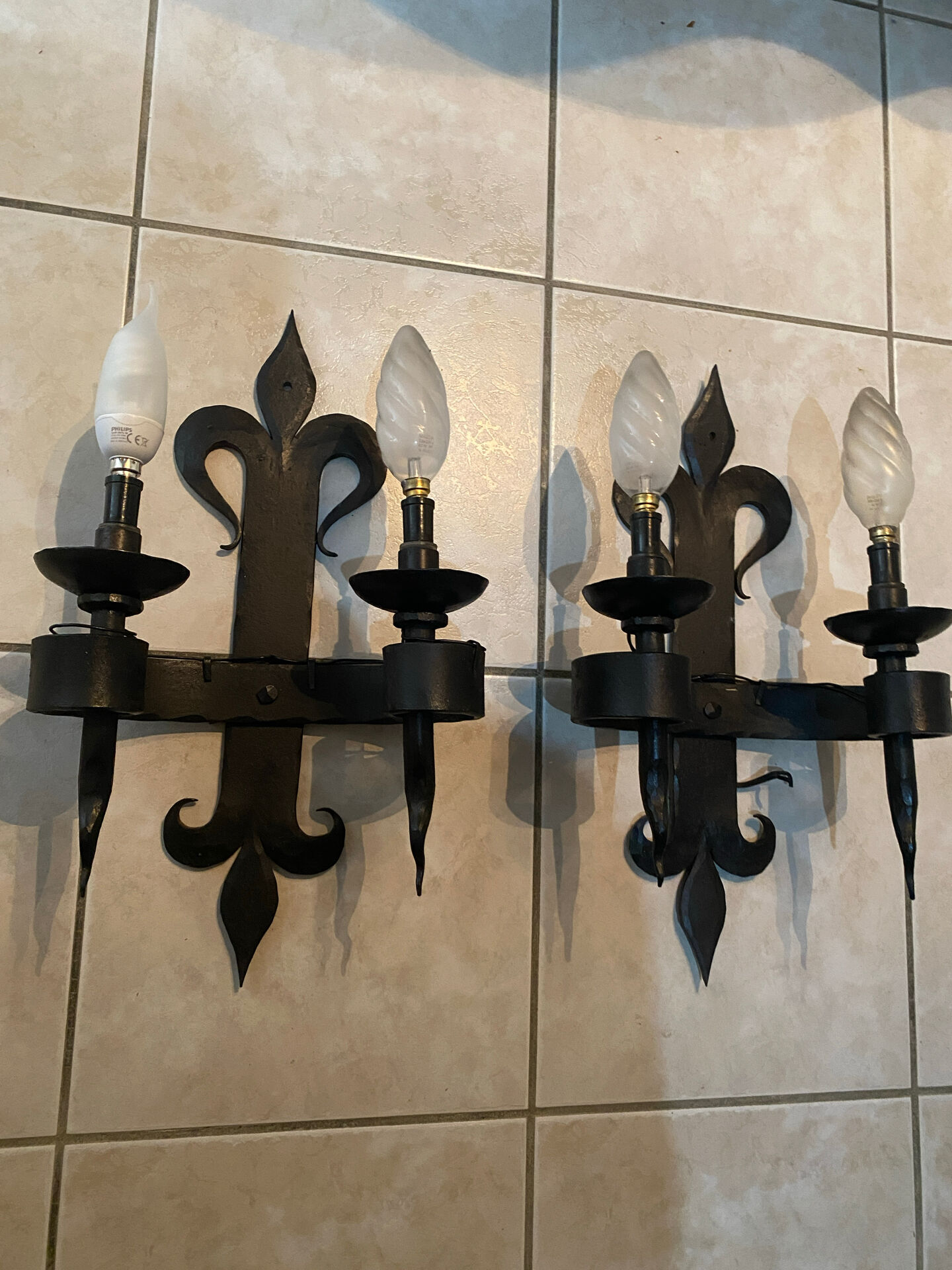 Pair of wrought iron wall lights in fleur-de-lis château style.