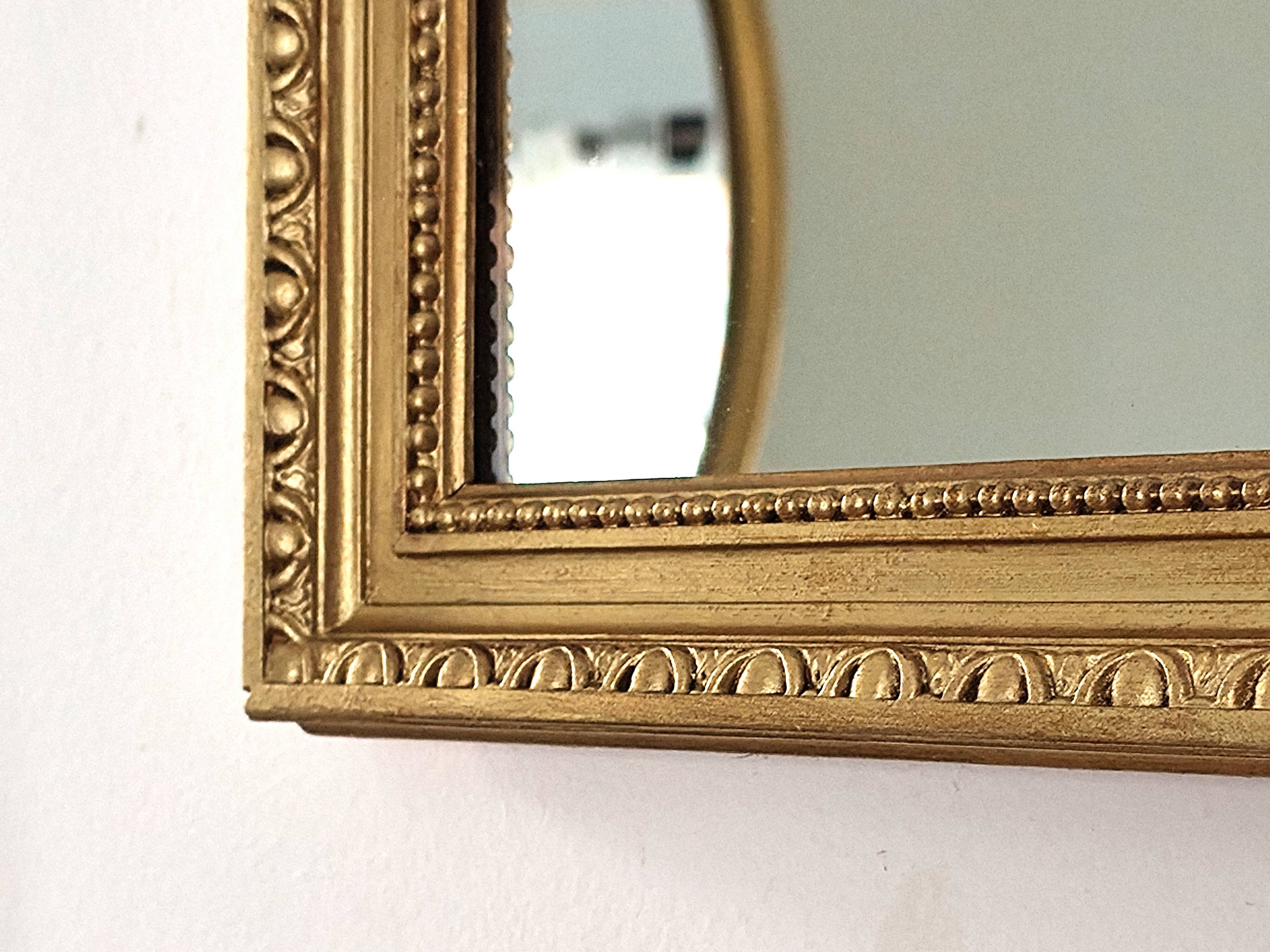 Antique mirror with a gilded frame and beaded border.