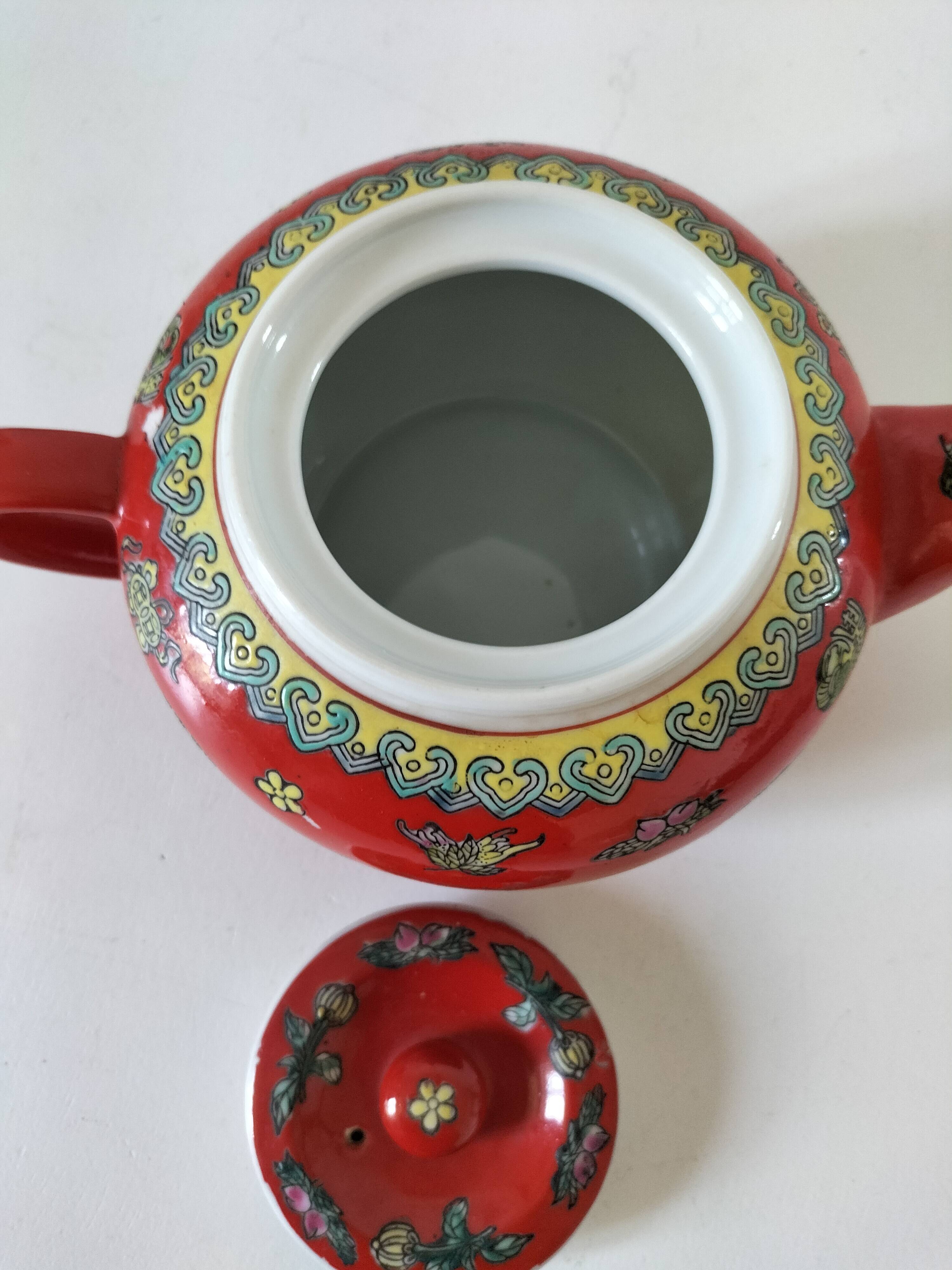 Vintage red Chinese teapot decorated with dragons and symbols.