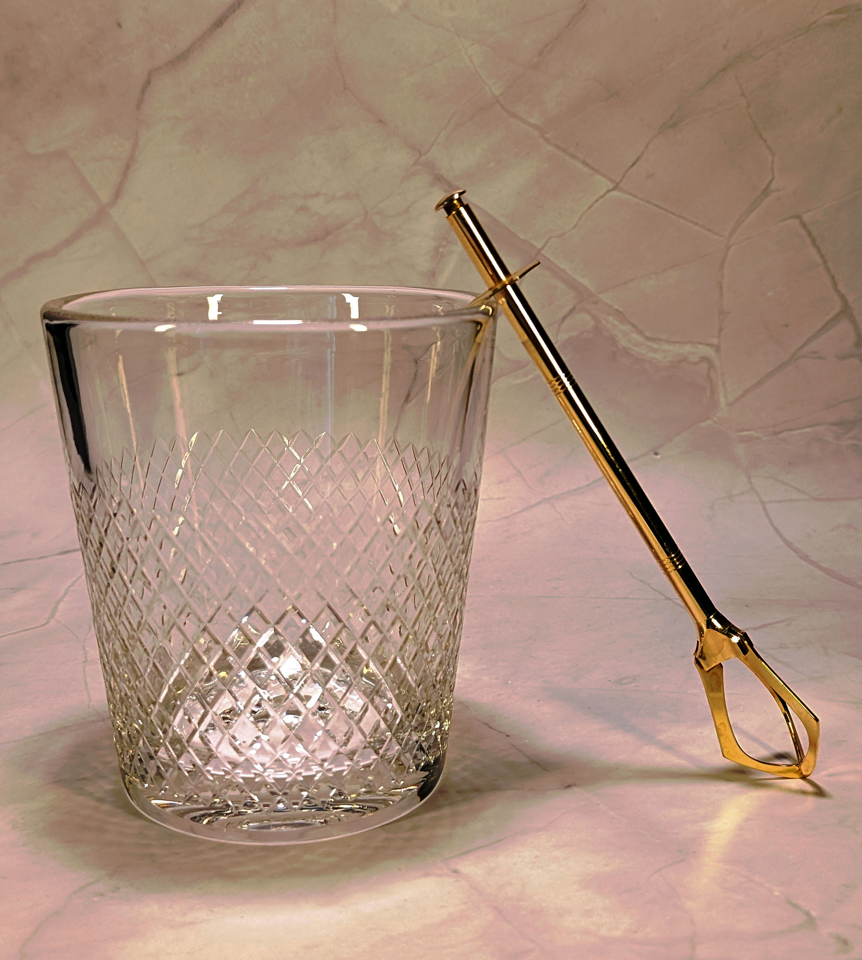 Vintage crystal ice bucket with gold tongs.