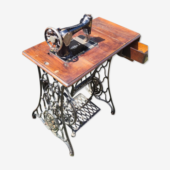 Machine a coudre Singer à navette rotative posée sur sa table d'origine munie d'un pédalier.