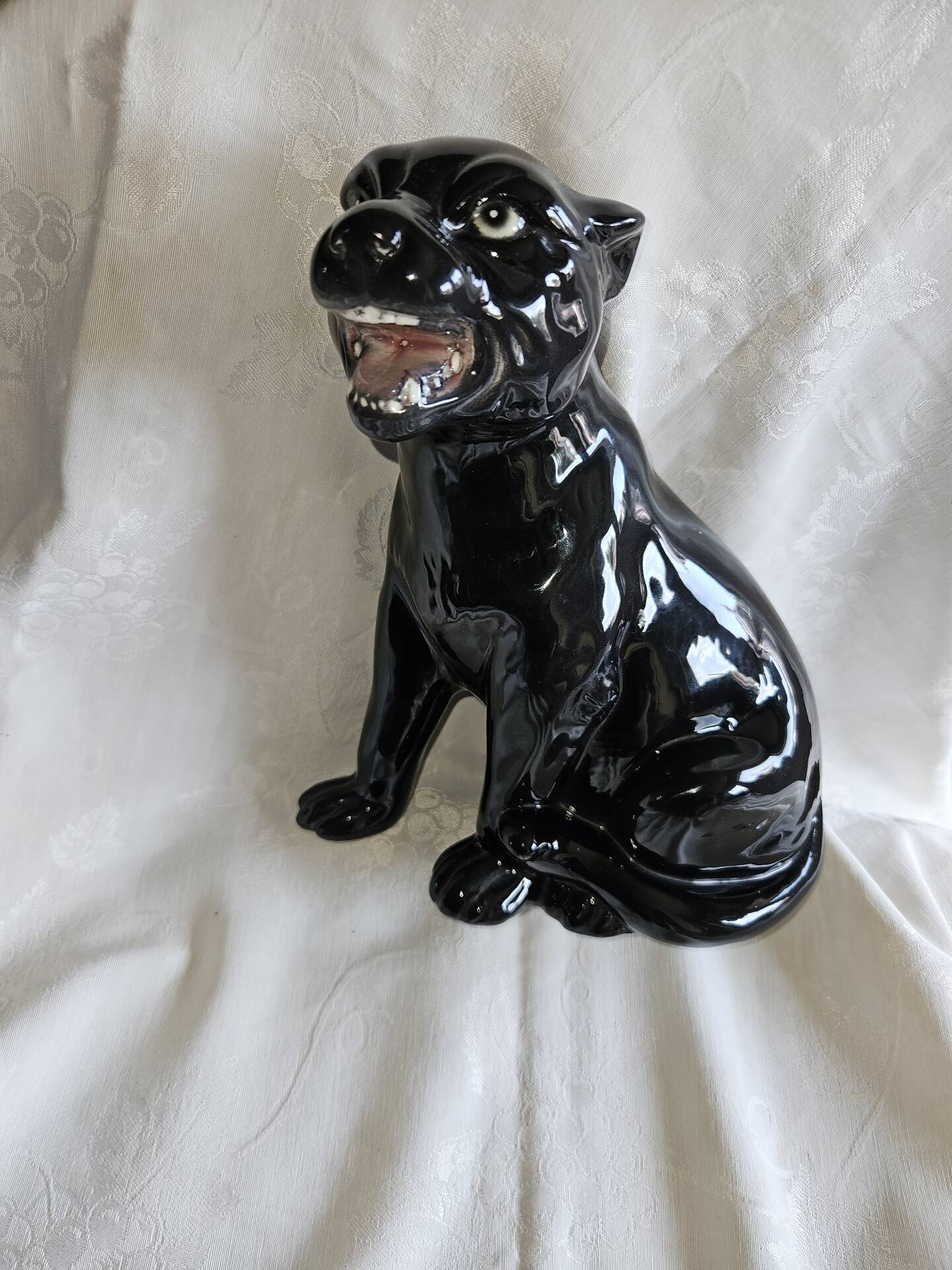 Statue of a roaring panther/leopard sitting in black glazed ceramic.