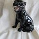 Statue of a roaring panther/leopard sitting in black glazed ceramic.