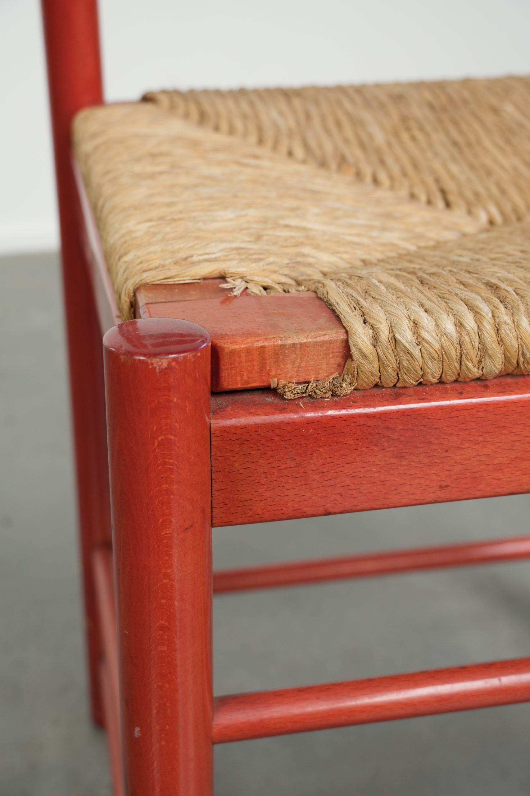Red vintage wooden chair from the 1970s with a woven wicker seat
