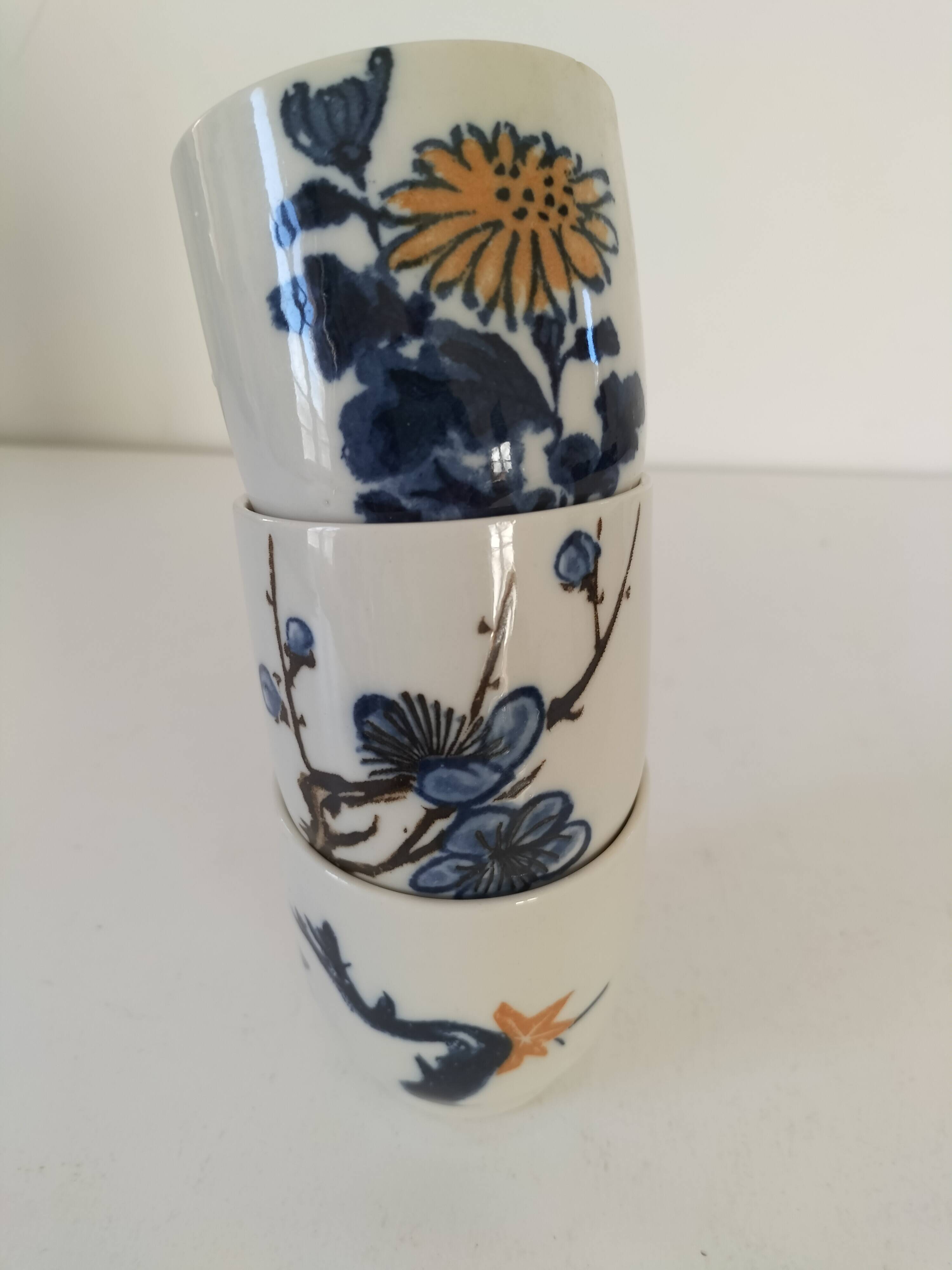 Set of three hand-painted porcelain cups with floral patterns.