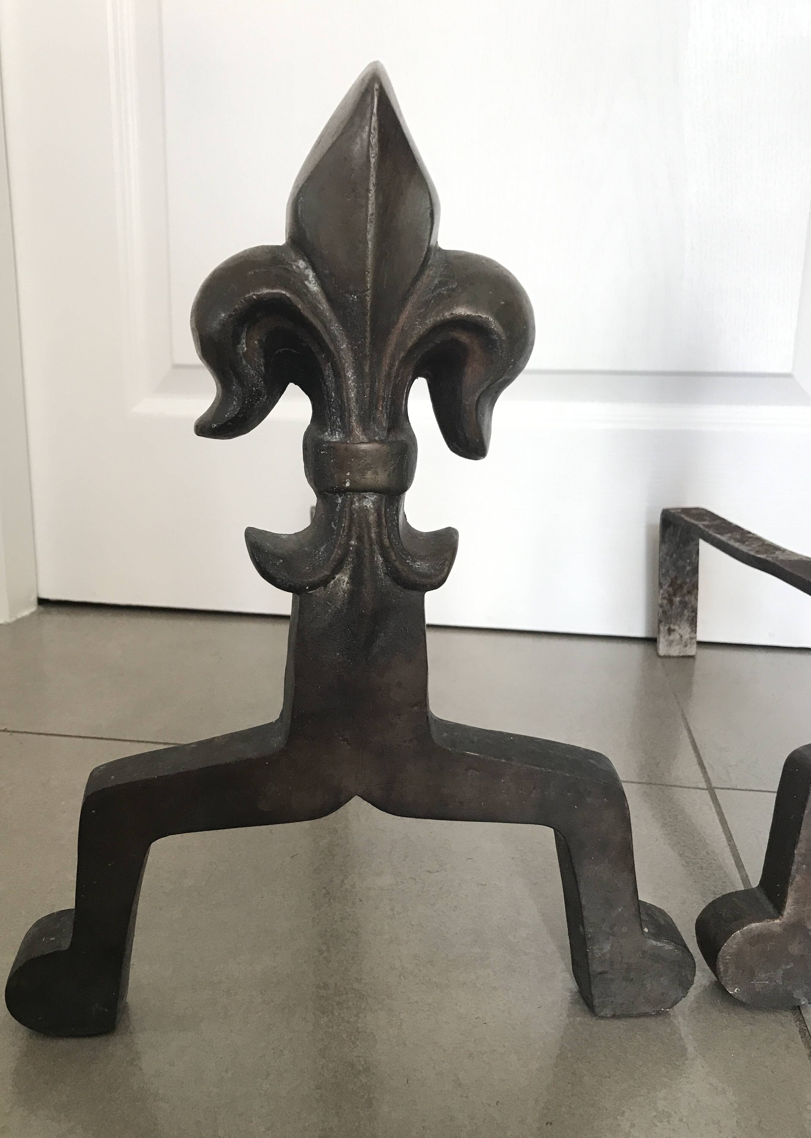 Pair of bronze fireplace firedogs with fleur-de-lys decor, art deco