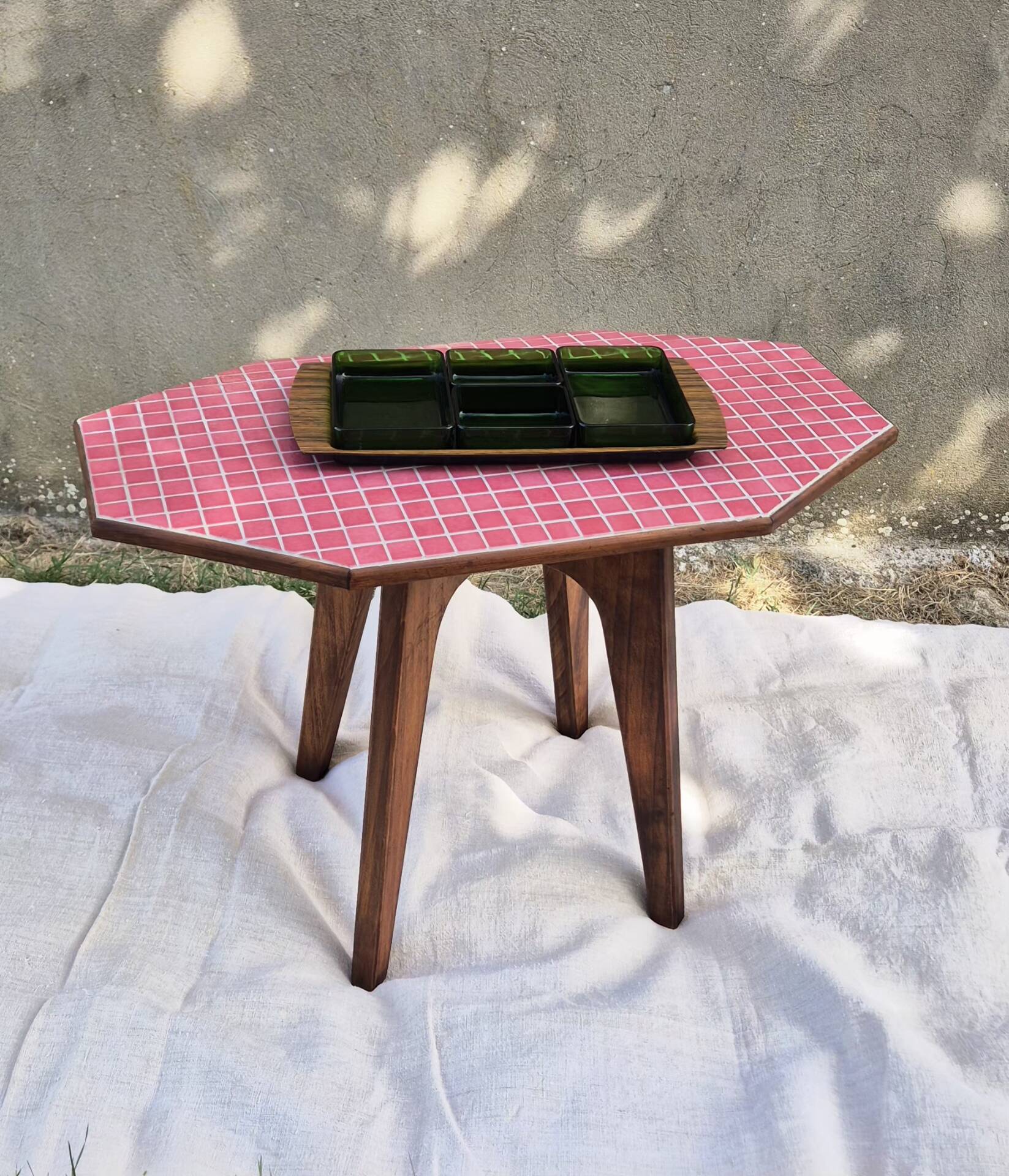 Small Scandinavian side table with wood and pink tiles, with tapered legs.
