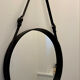Round mirror covered in black leather in the style of Jacques Adnet.