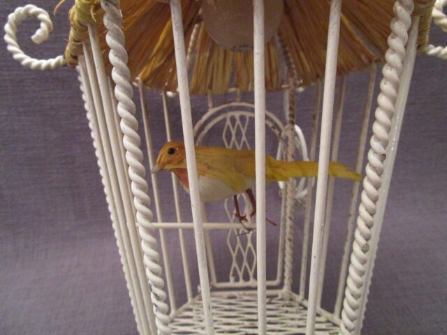 Vintage suspension cage has metal birds and raffia
