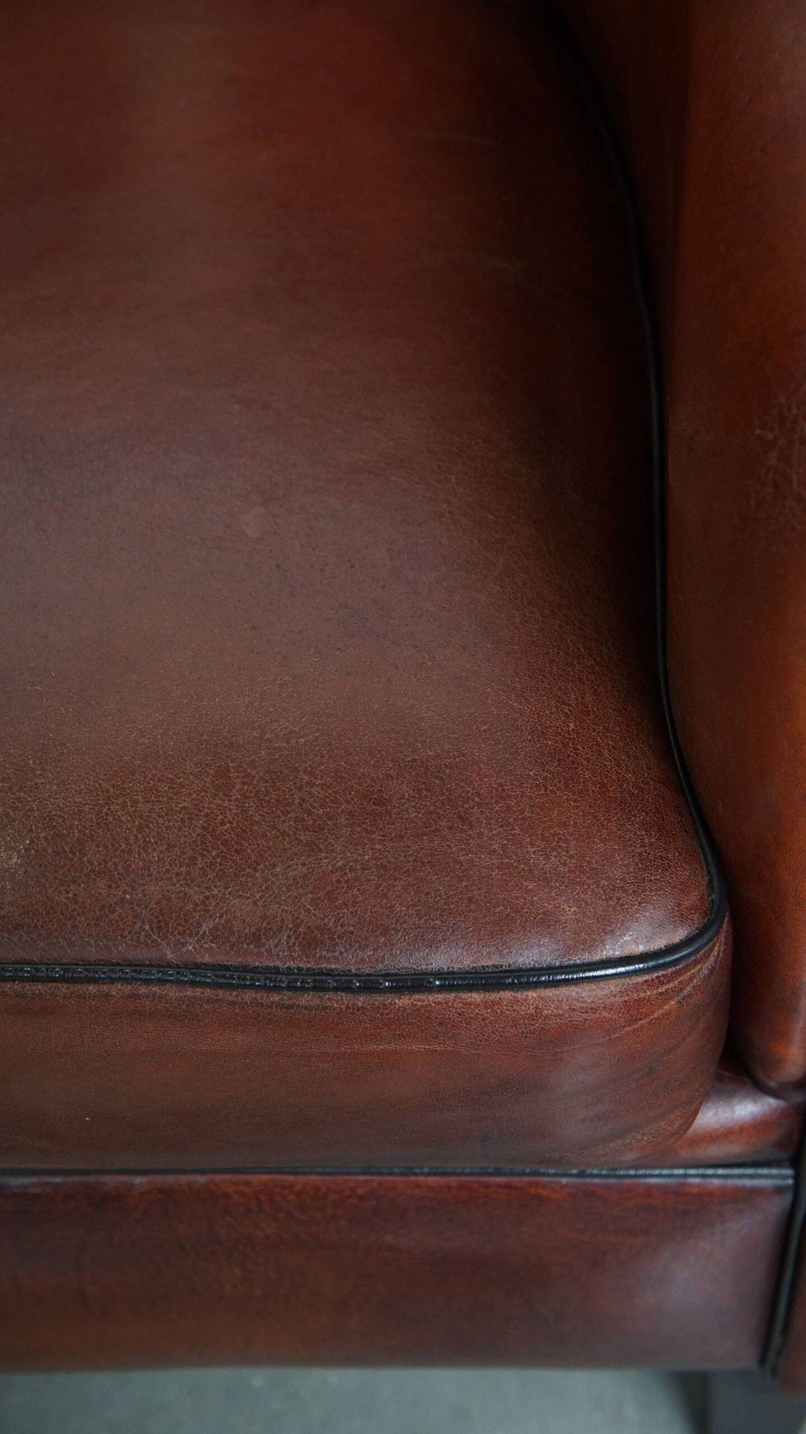 Sheepskin club armchair in a warm deep colour finished with black piping