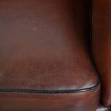 Sheepskin club armchair in a warm deep colour finished with black piping