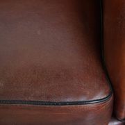 Sheepskin club armchair in a warm deep colour finished with black piping
