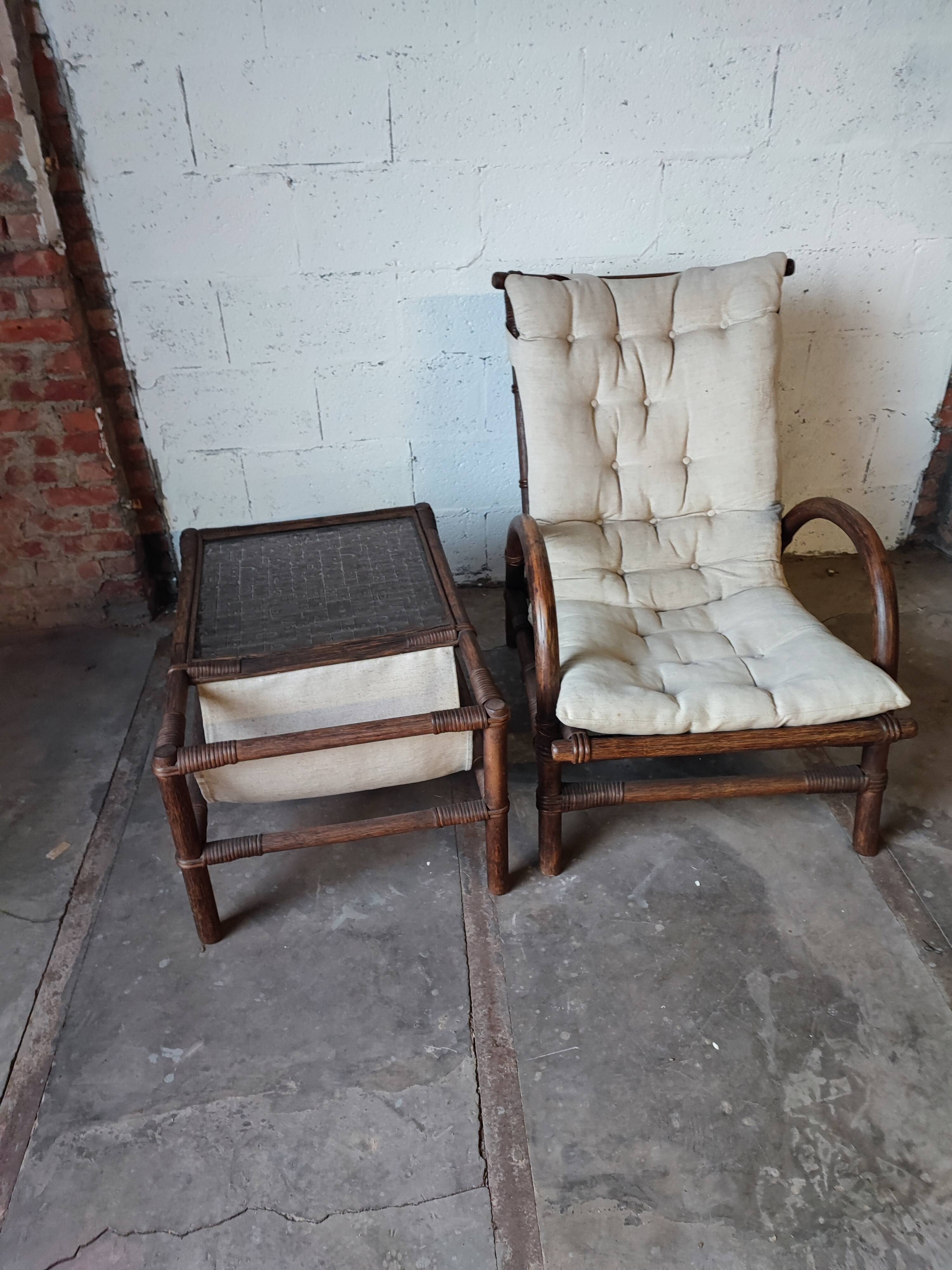 Relaxed armchair in bamboo and rattan with its small side table. Beige linen cushion.