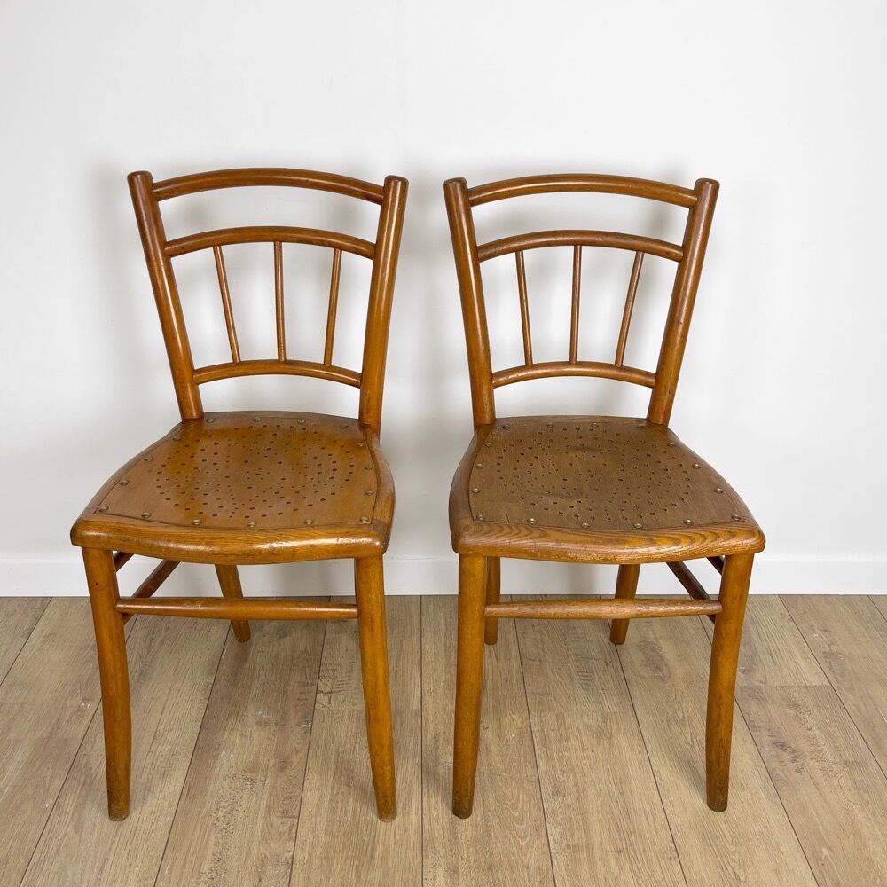 Pair of curved wood bistro chairs and studded and perforated seat
