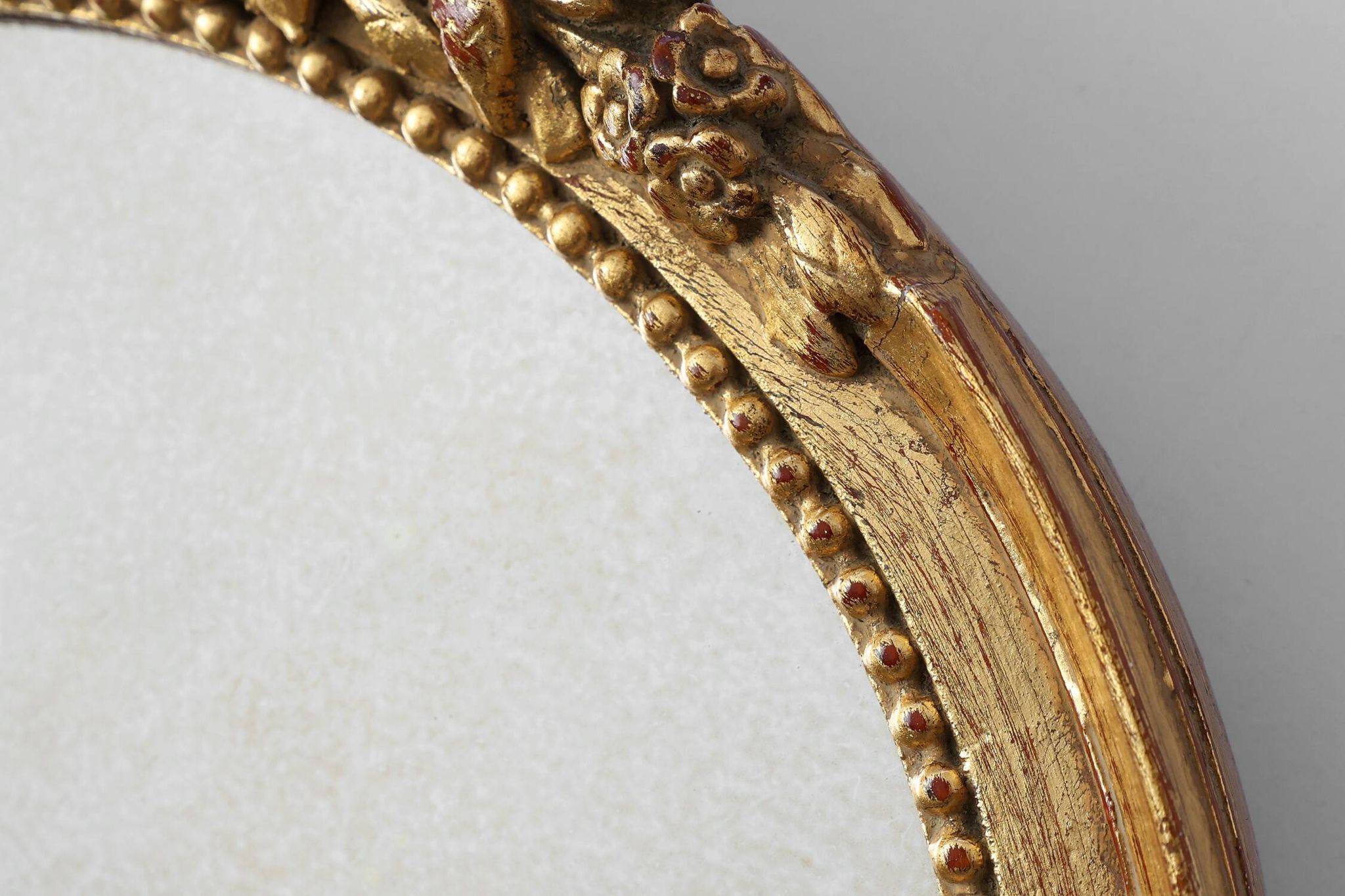 Oval giltwood mirror with rococo-style floral crest, mid-20th century