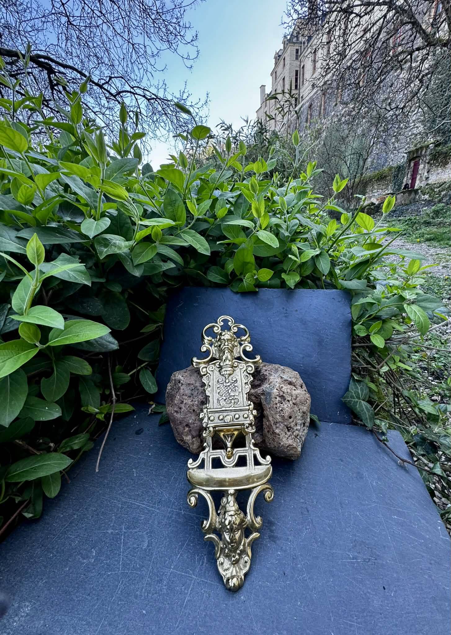 Brass magazine rack with baroque mask, wall-mounted match holder.