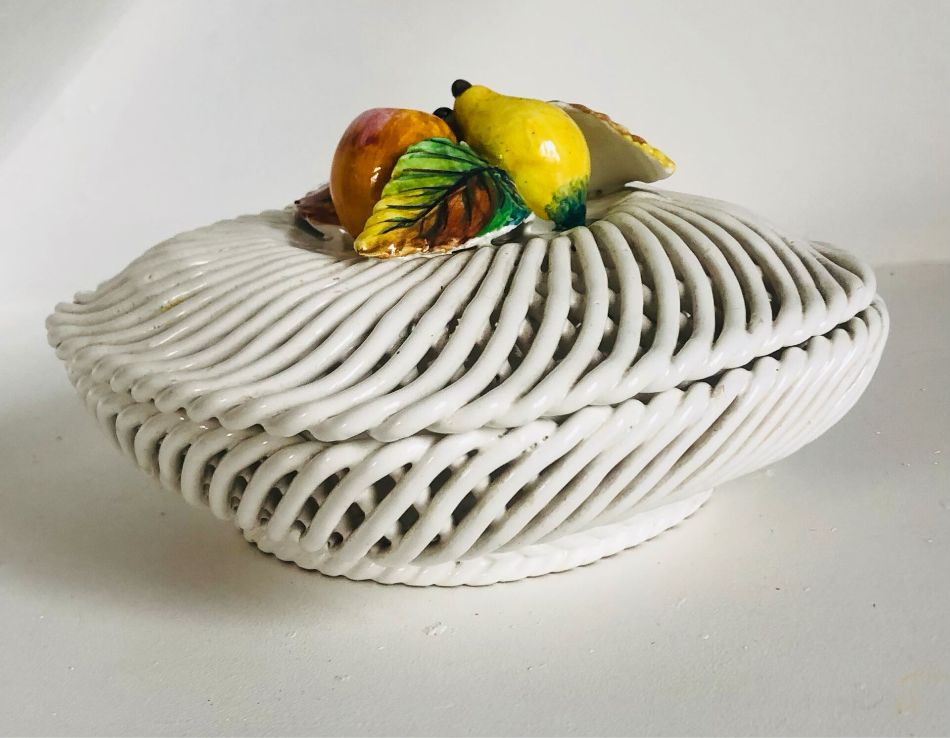 Covered basket in white woven ceramic and fruit slip.