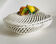 Covered basket in white woven ceramic and fruit slip.