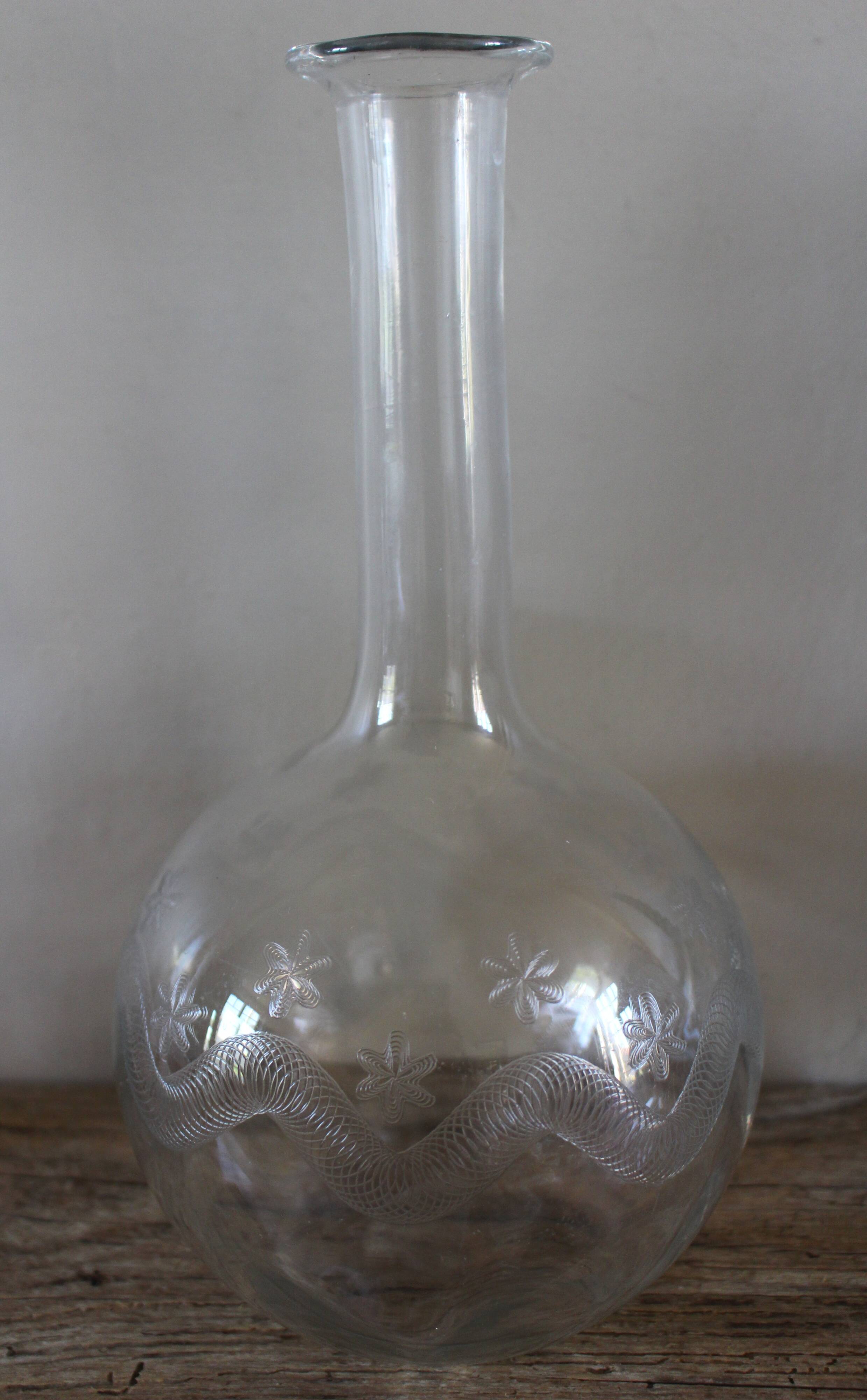 Antique glass carafe with a round belly and floral neck.