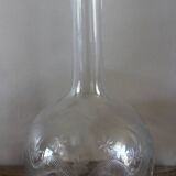 Antique glass carafe with a round belly and floral neck.