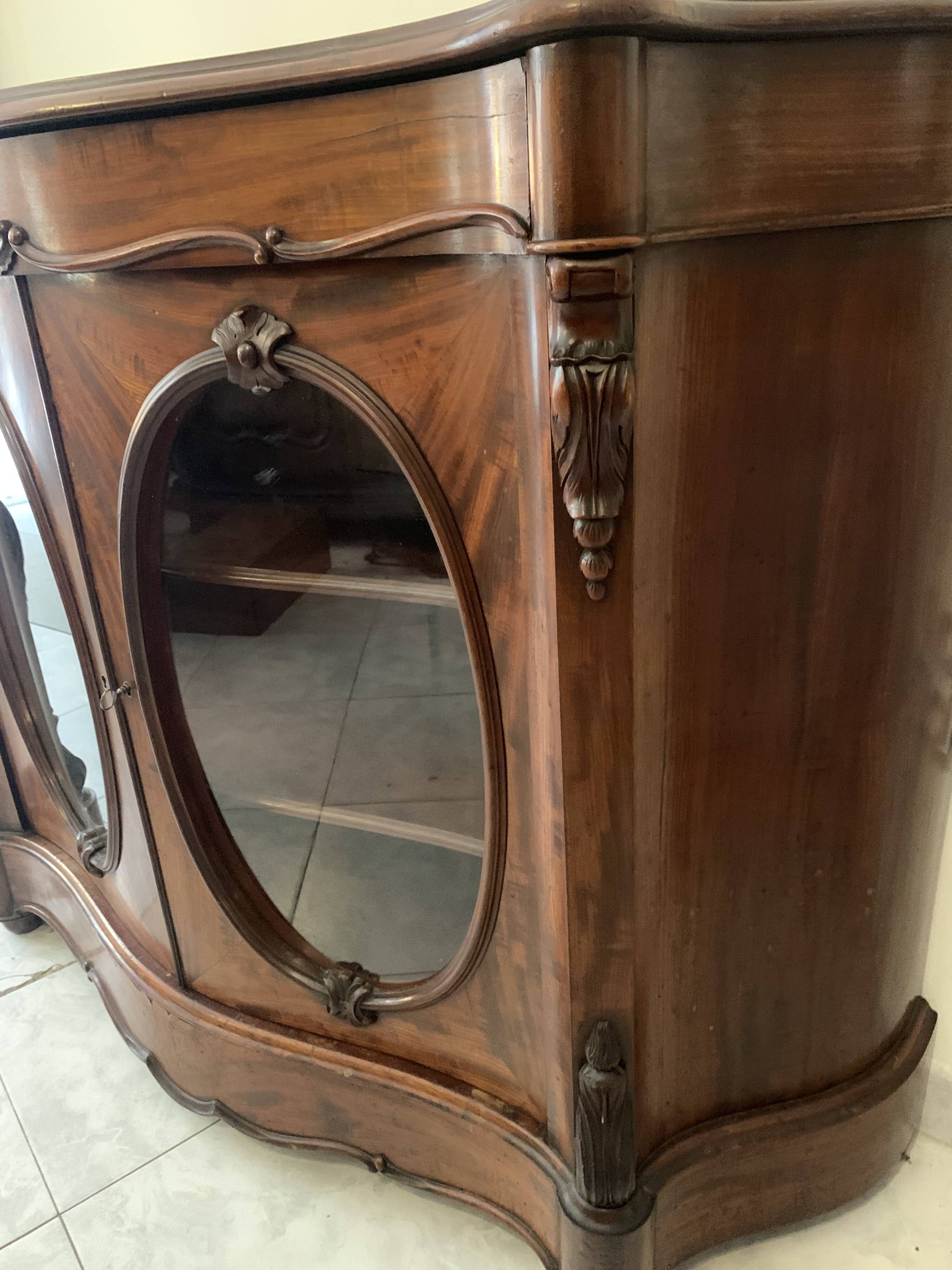 Curved mahogany display cabinet from the Napoleon III period. It has two doors and two shelves.