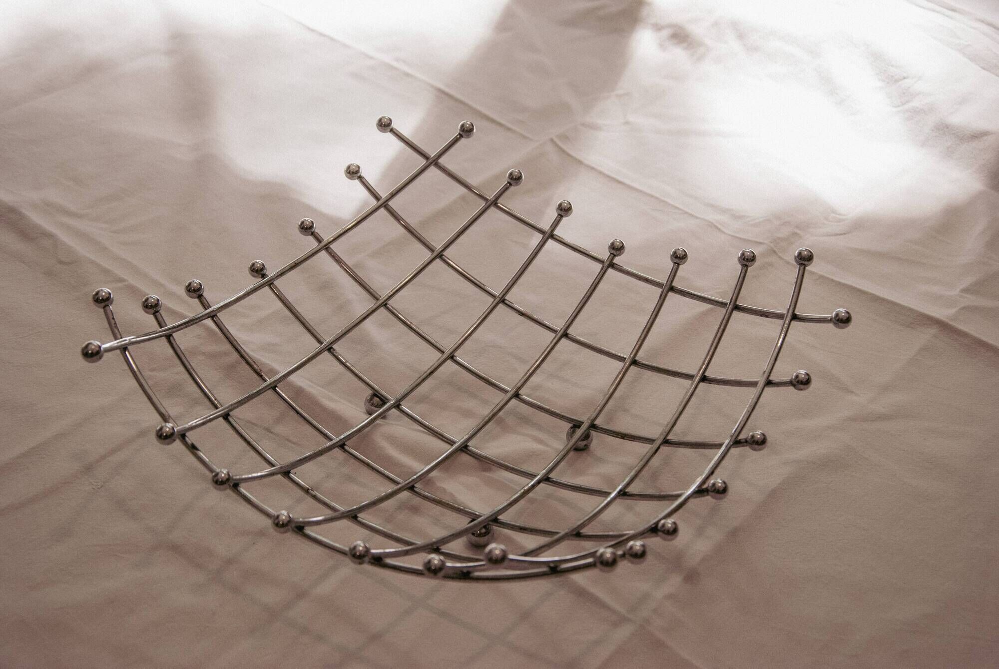 Curved grid fruit bowl, chrome metal and beads.