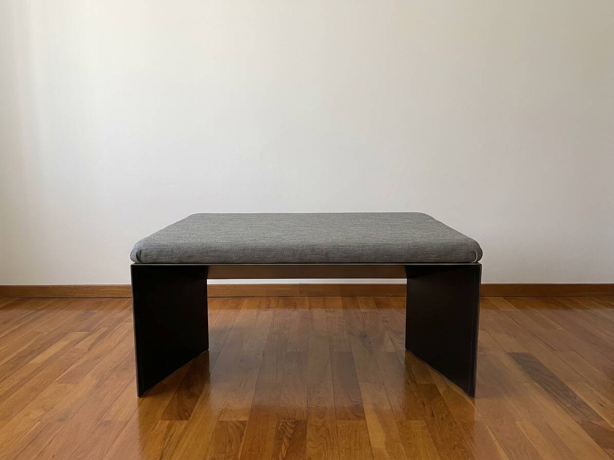 Minimalist/industrial coffee table with a black metal frame and a grey fabric top.