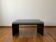 Minimalist/industrial coffee table with a black metal frame and a grey fabric top.