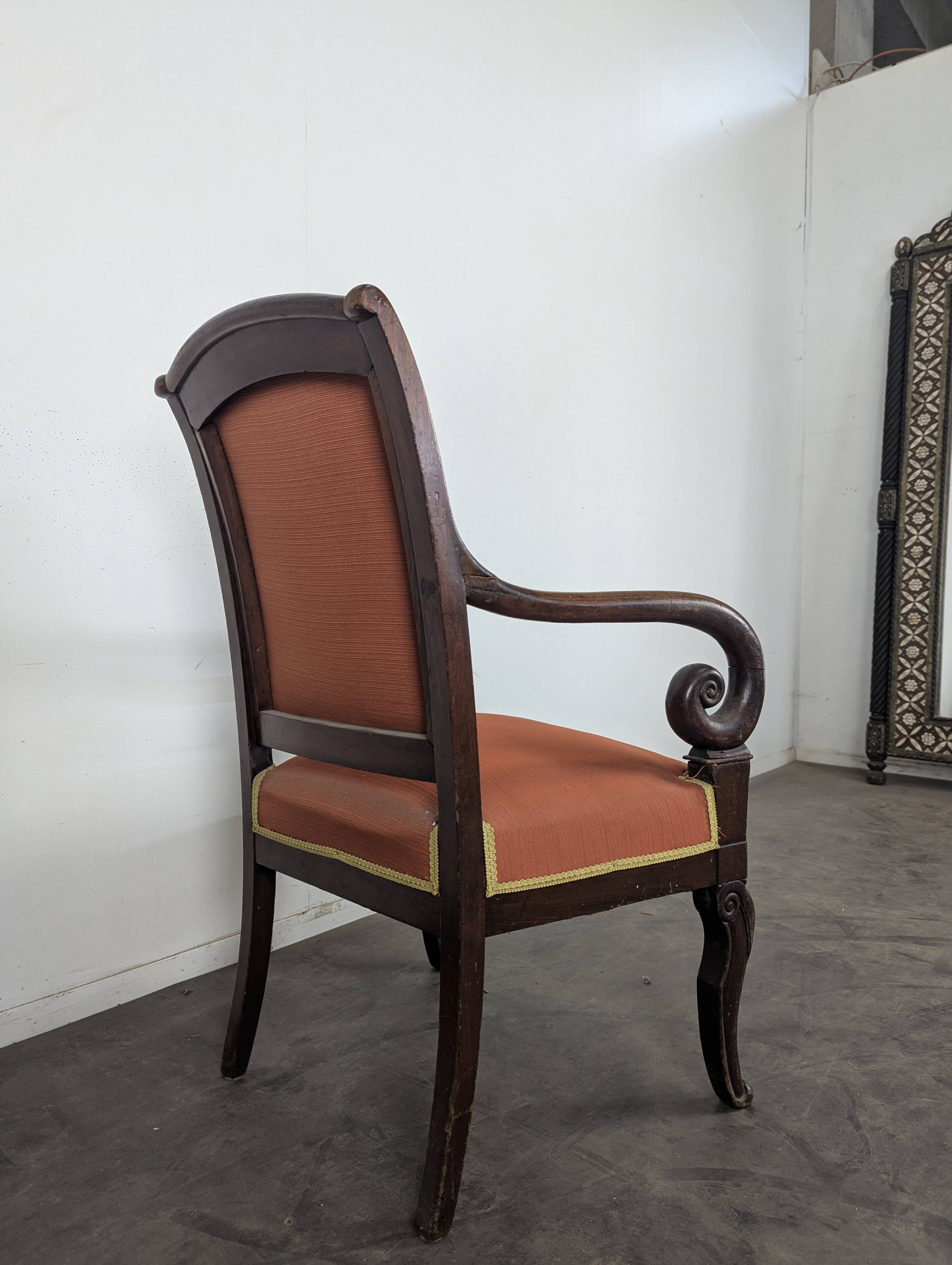 Restoration armchair in mahogany with cross arms and orange fabric.