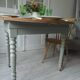 Raised walnut table with drop-leaf top, base on verdigris castors.