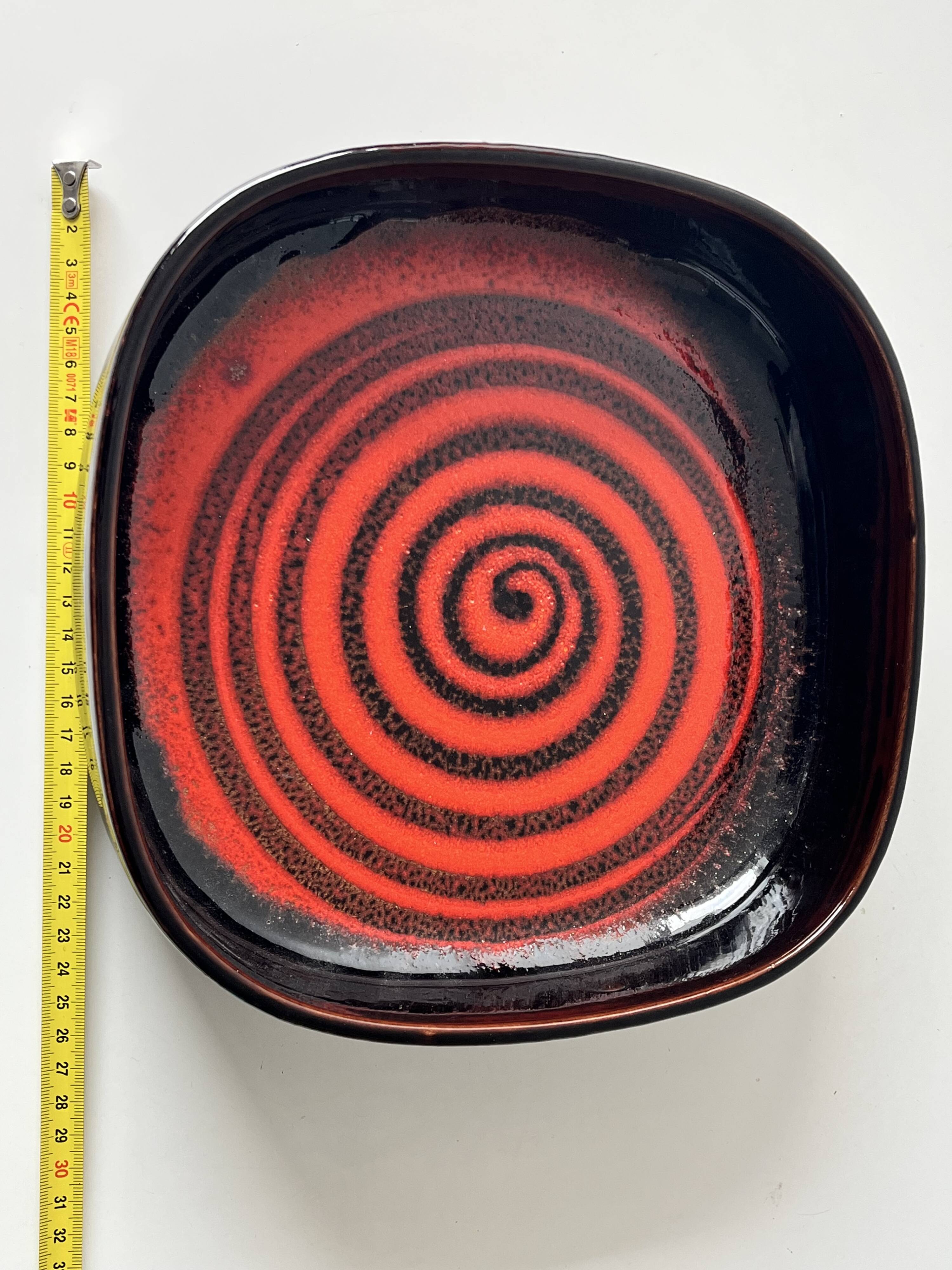 Large decorative ceramic catchall with red and black spiral pattern.