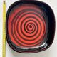 Large decorative ceramic catchall with red and black spiral pattern.