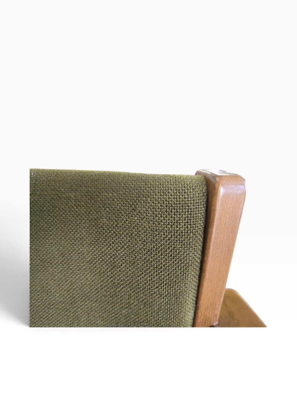 Vintage wooden chair with olive green seat and armrests.