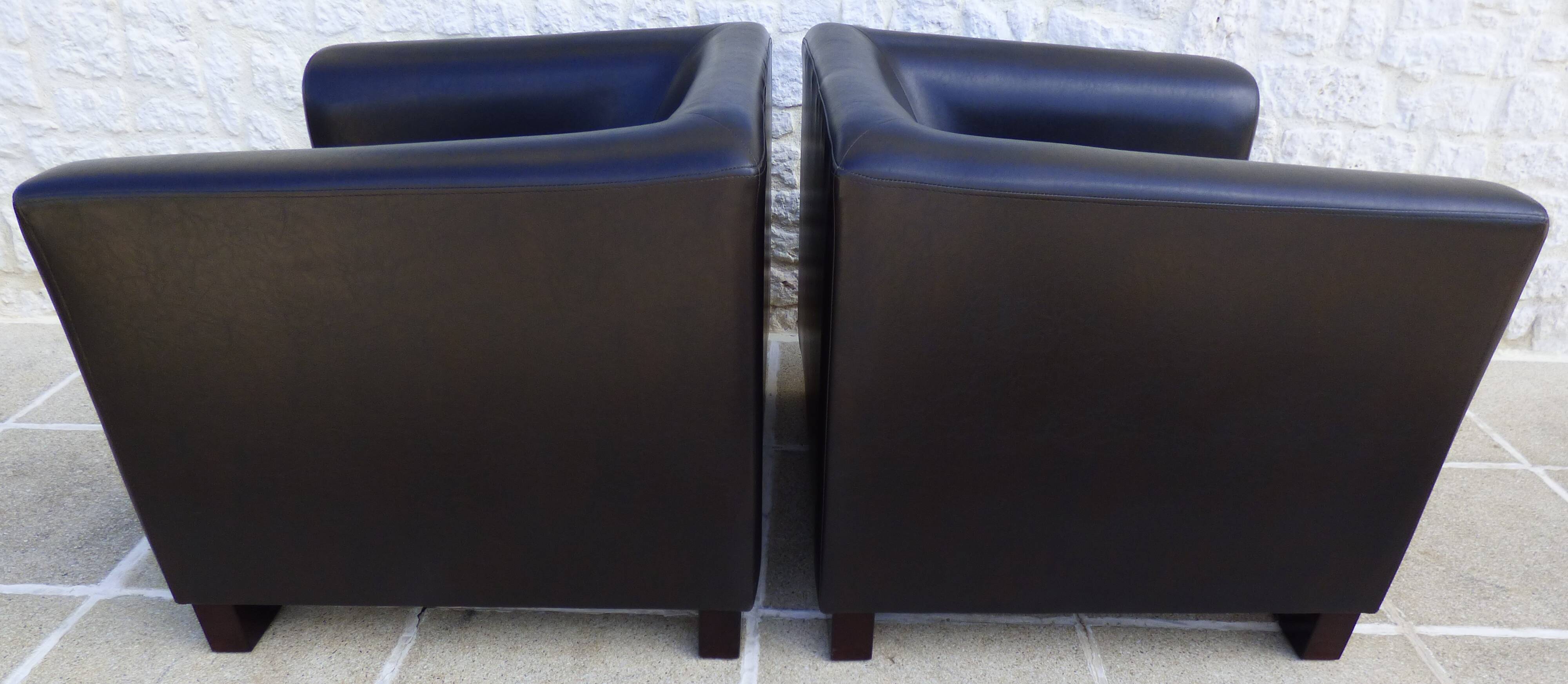 2 club armchairs with a chocolate faux leather seat and backrest and wooden legs.