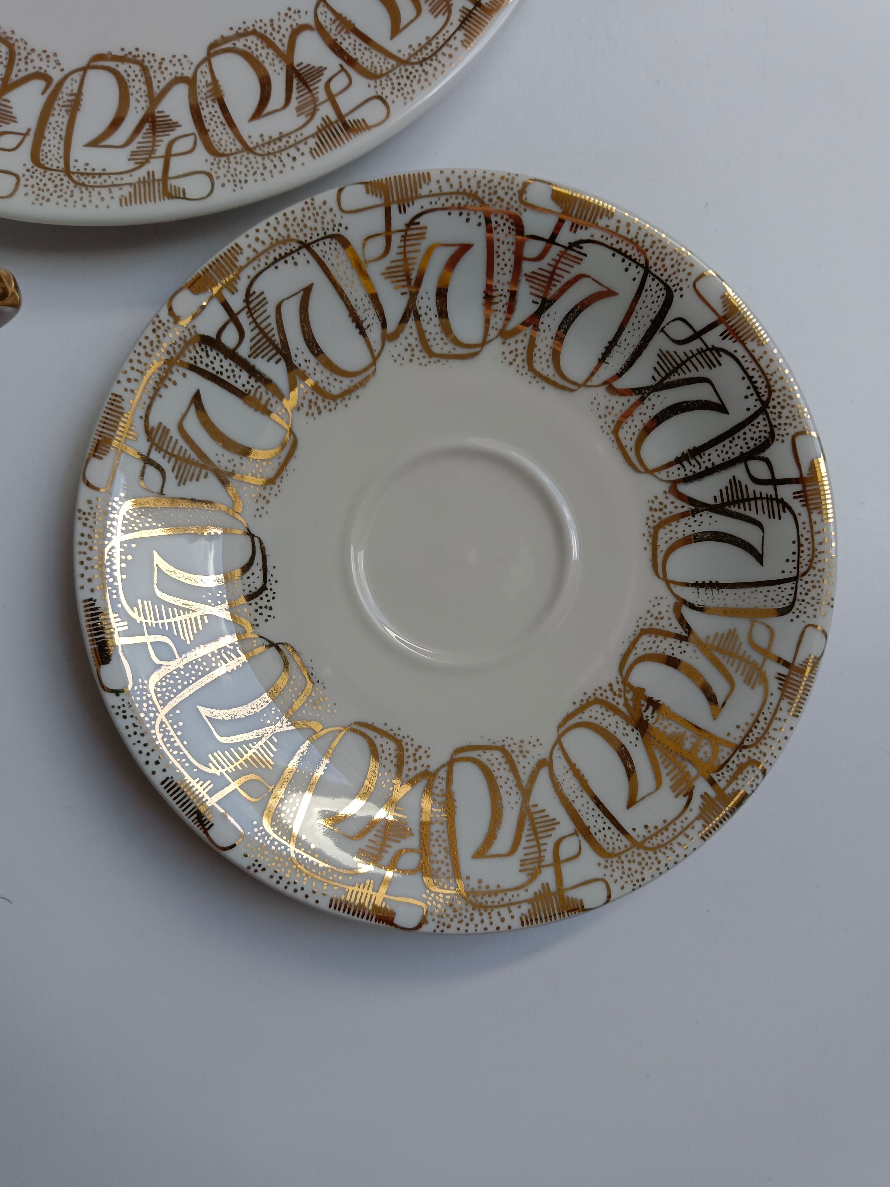 Solitaire tea cup, saucer, and dessert plate in white and gold.