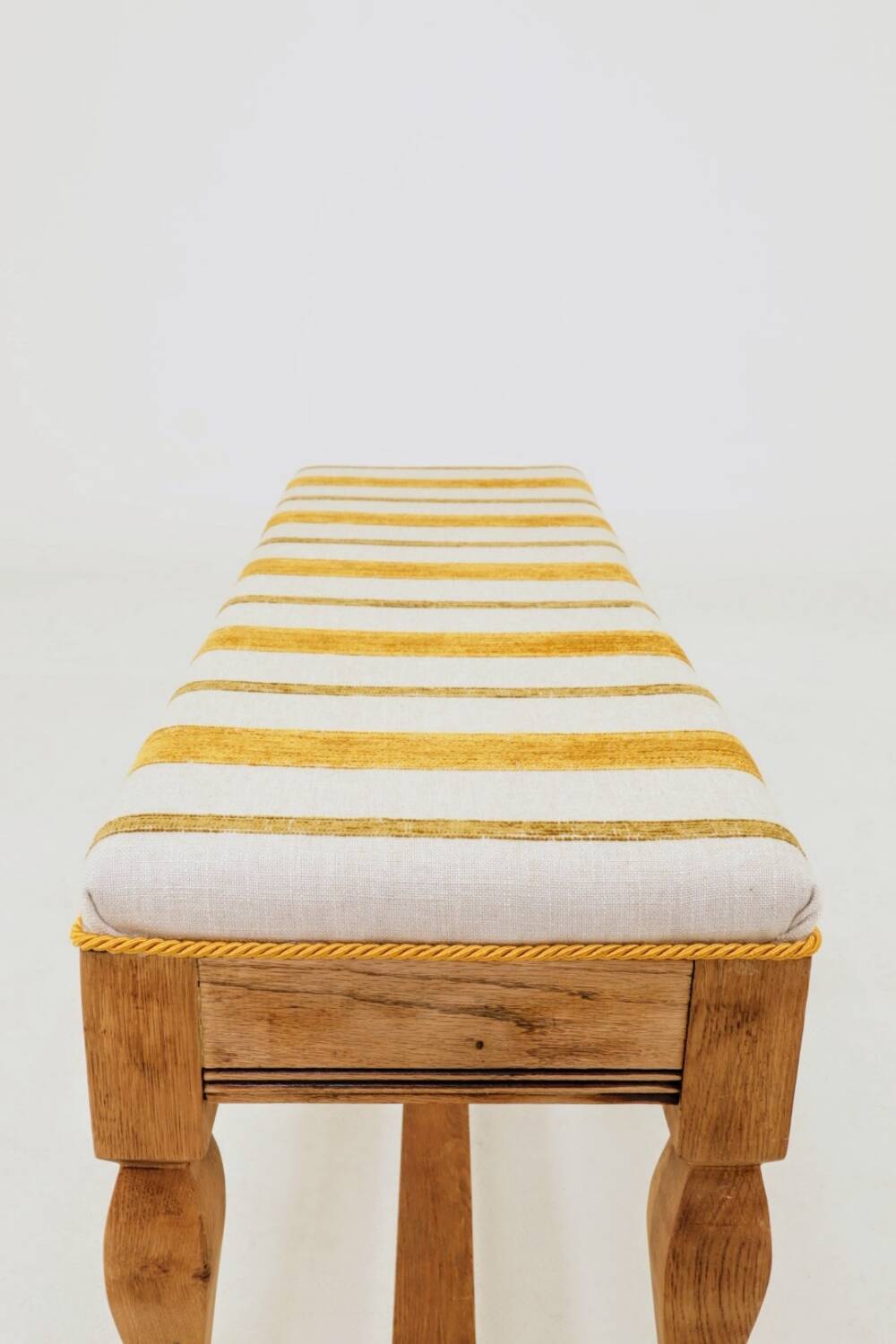 Vintage oak bench with striped linen fabric in a country style.