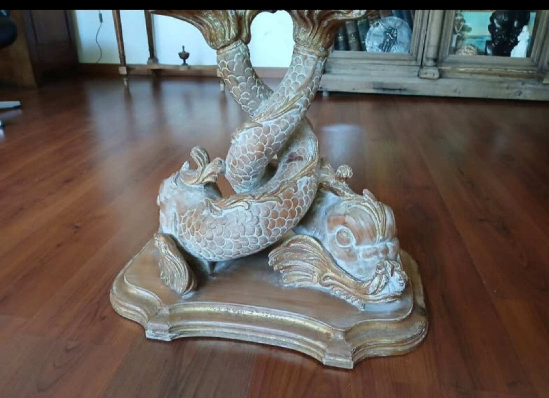 Glass table with carved wooden legs featuring intertwined fish.