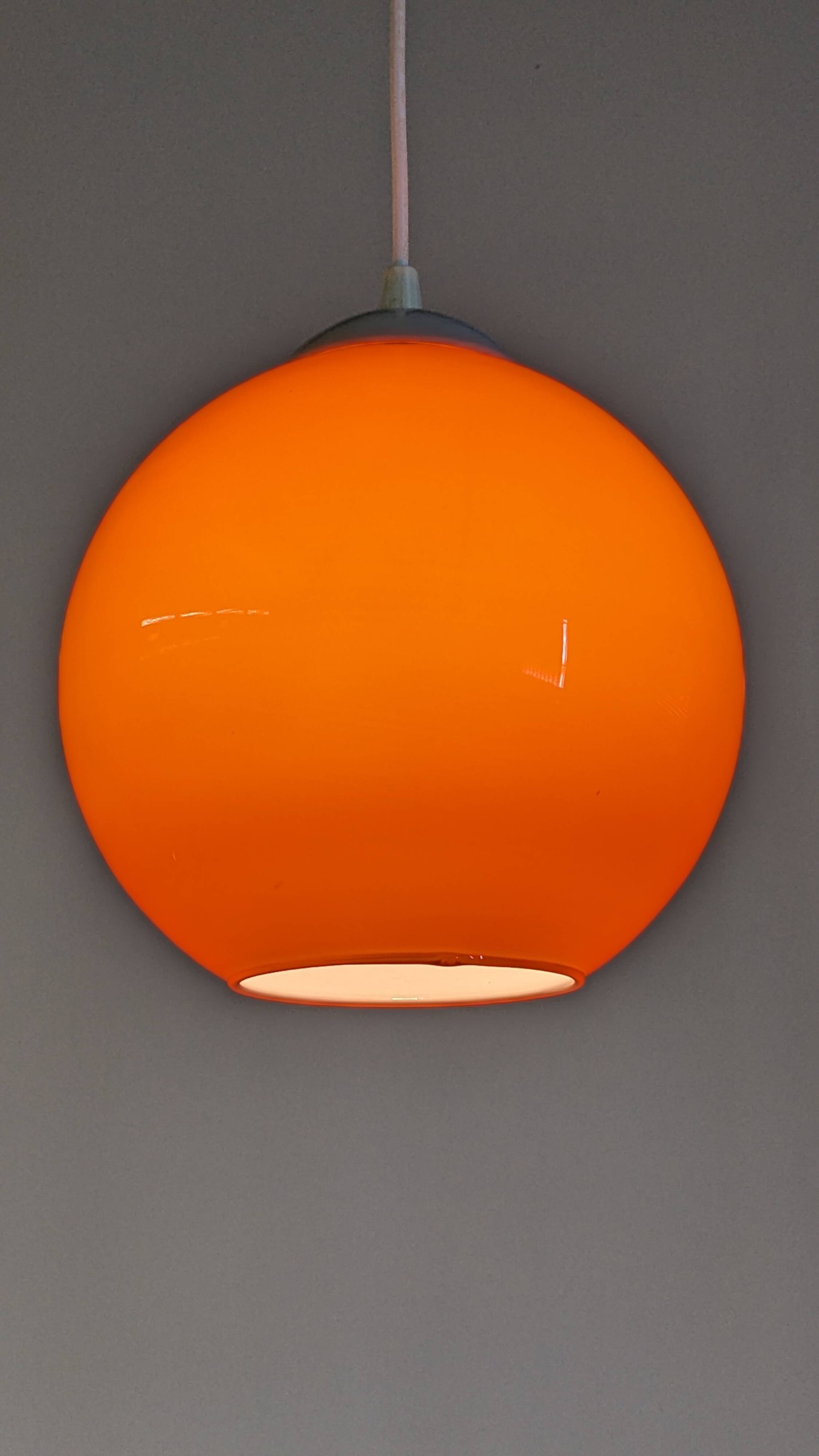 Pair of spherical pendant lights in orange opaline, France circa 1970.