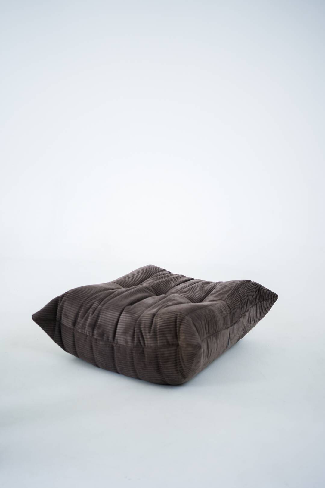 Ensemble de chaise et pouf Togo en velours côtelé marron.