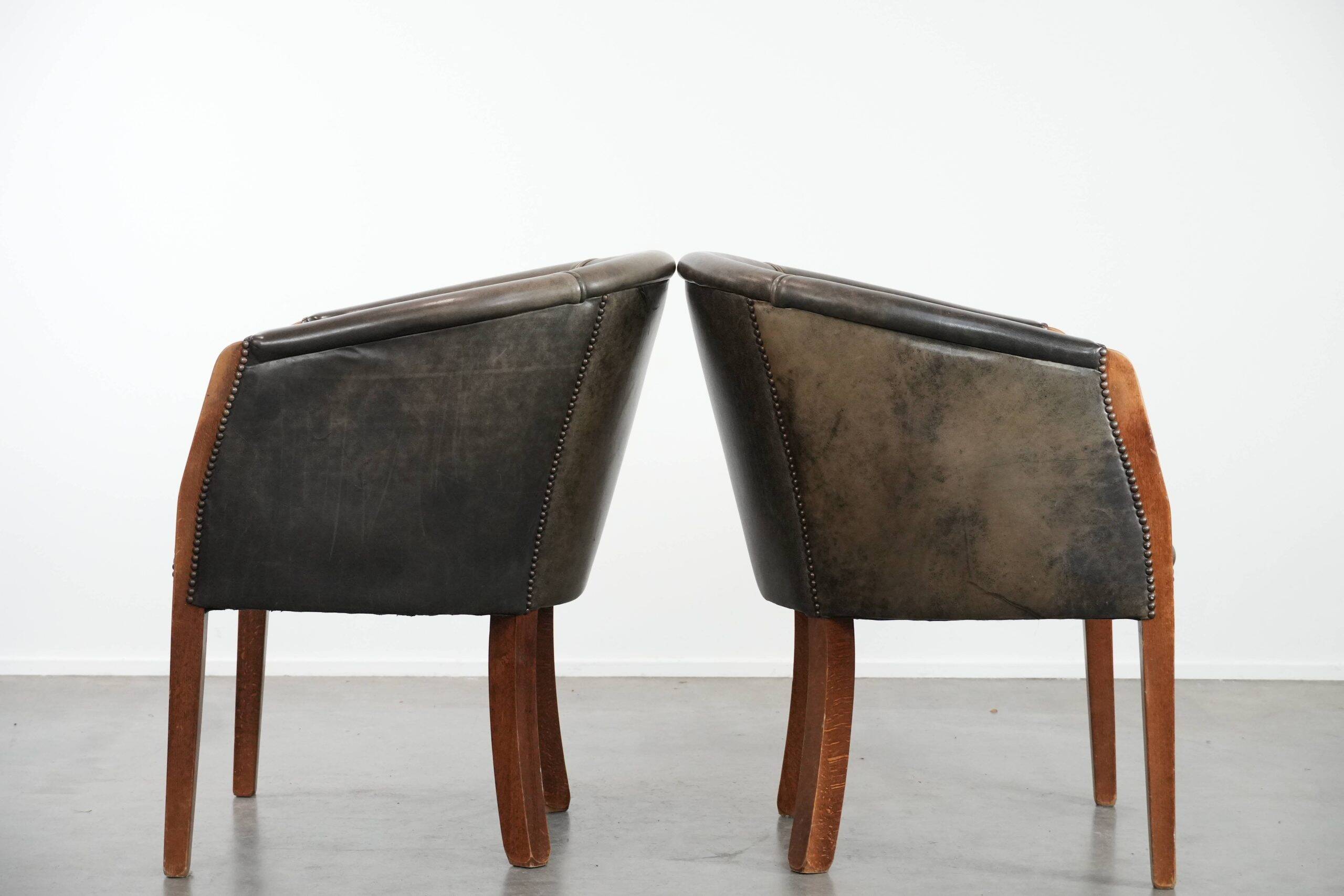 Set of two cowhide and wooden tub chairs with a sturdy colour scheme