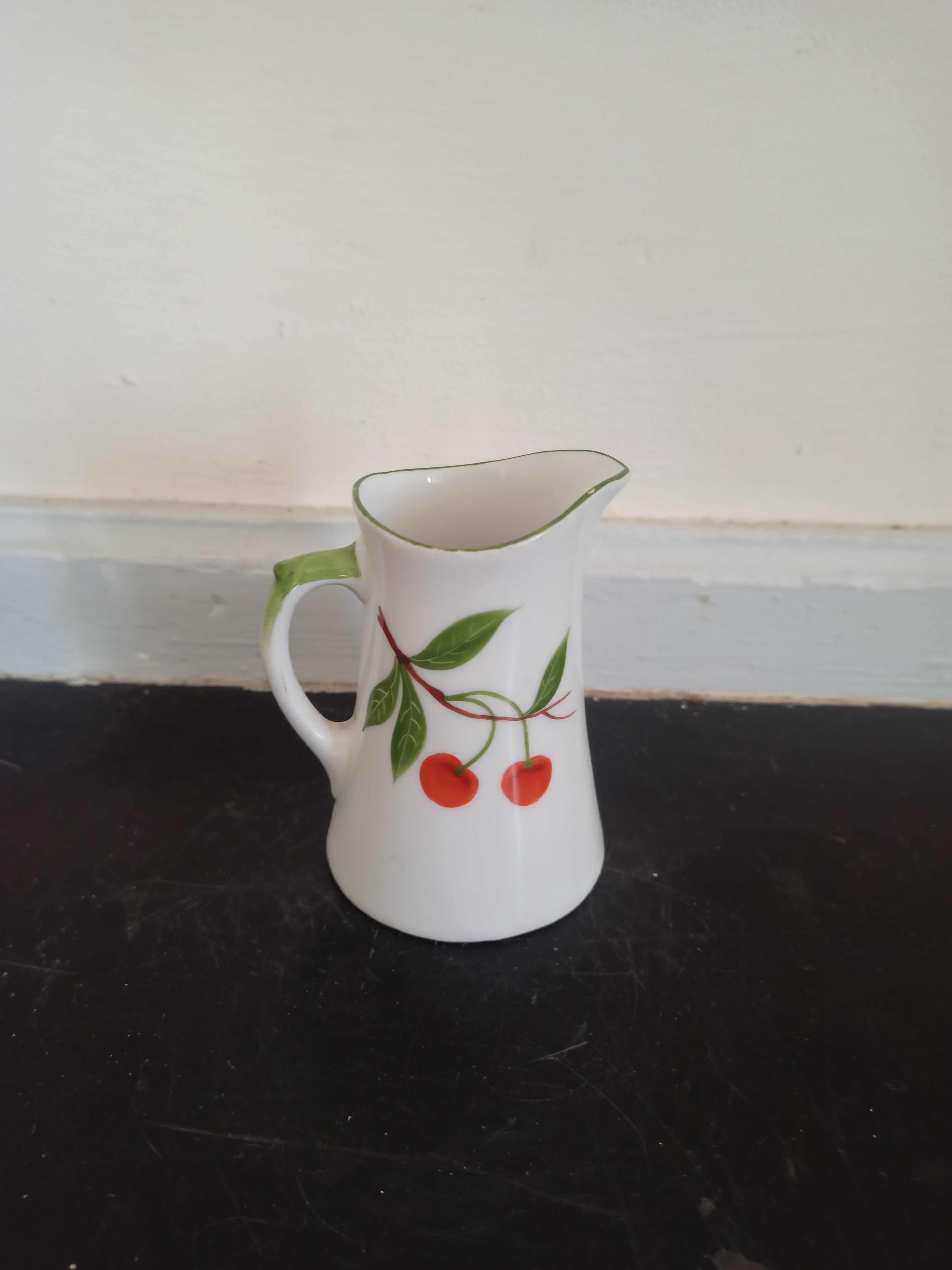 Small ancient porcelain pitcher decorated with cherries
