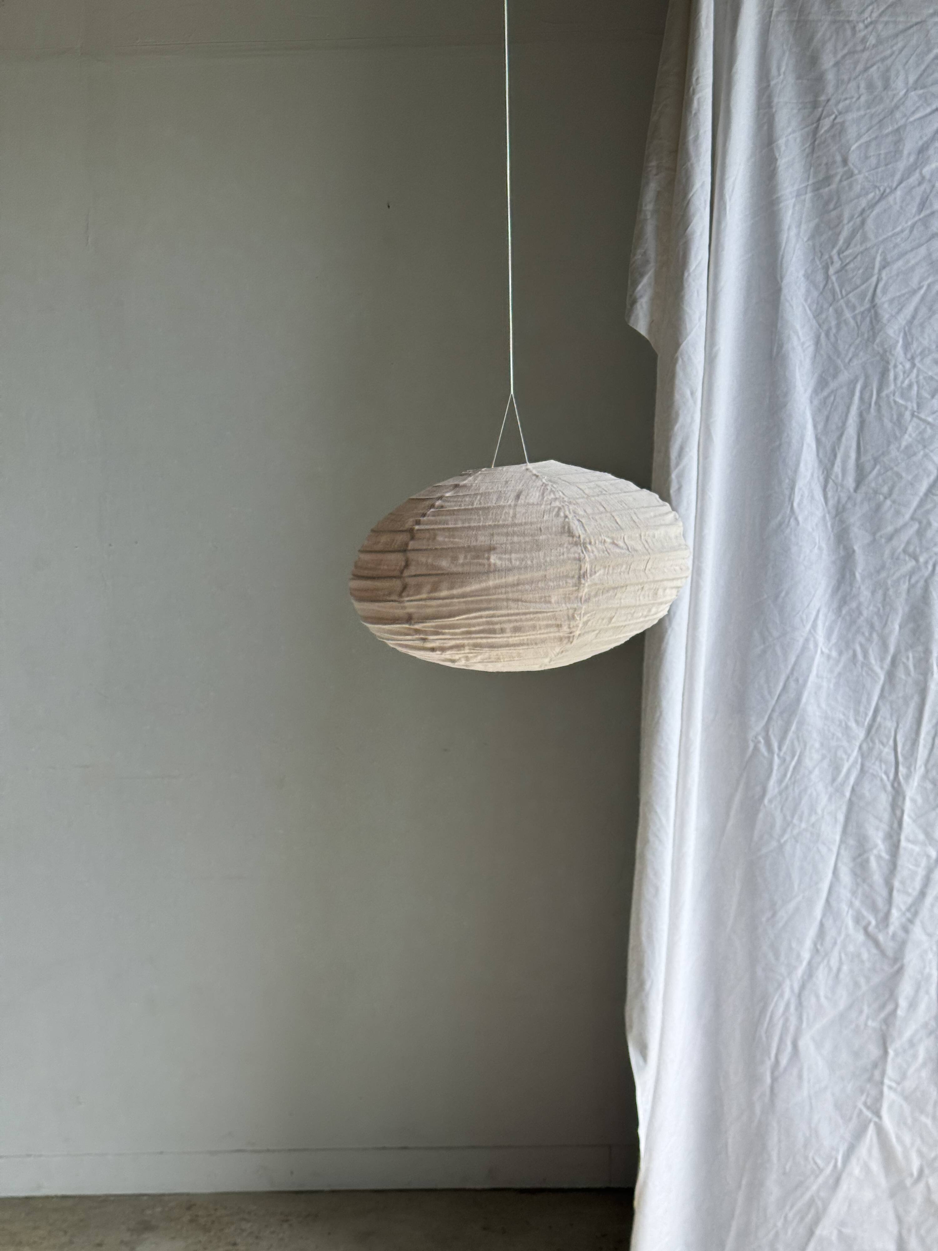 Average suspension in natural rattan and linen, Japanese-style, flattened oval in pink.