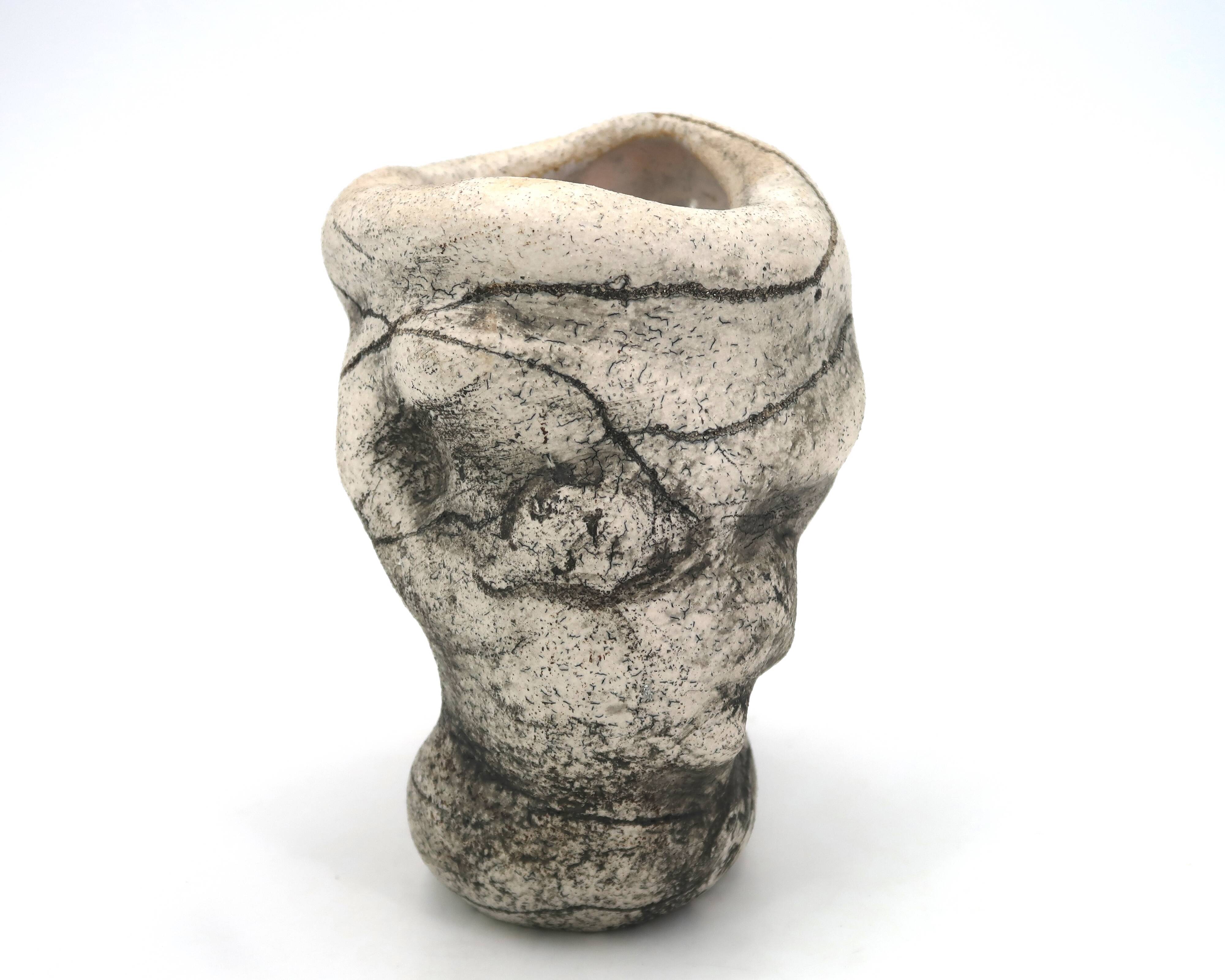 Ceramic vase sculpture decorated with faces and featuring a hole, 1980s.