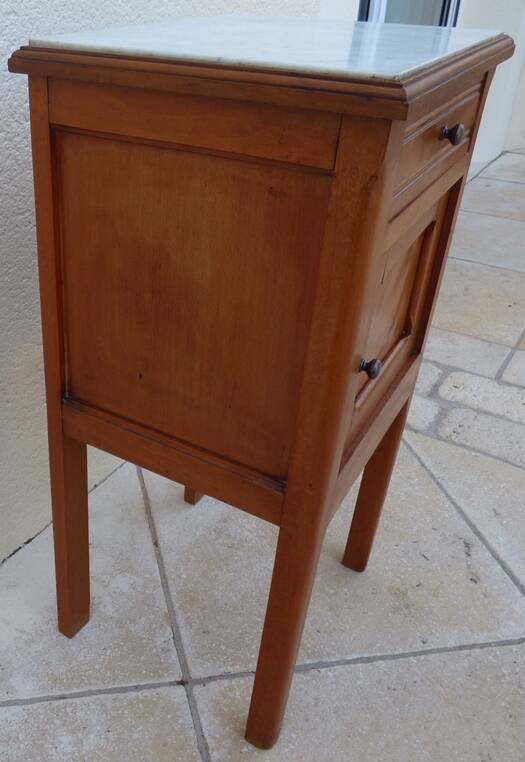 Antique bedside table with its marble top and white earthenware interior