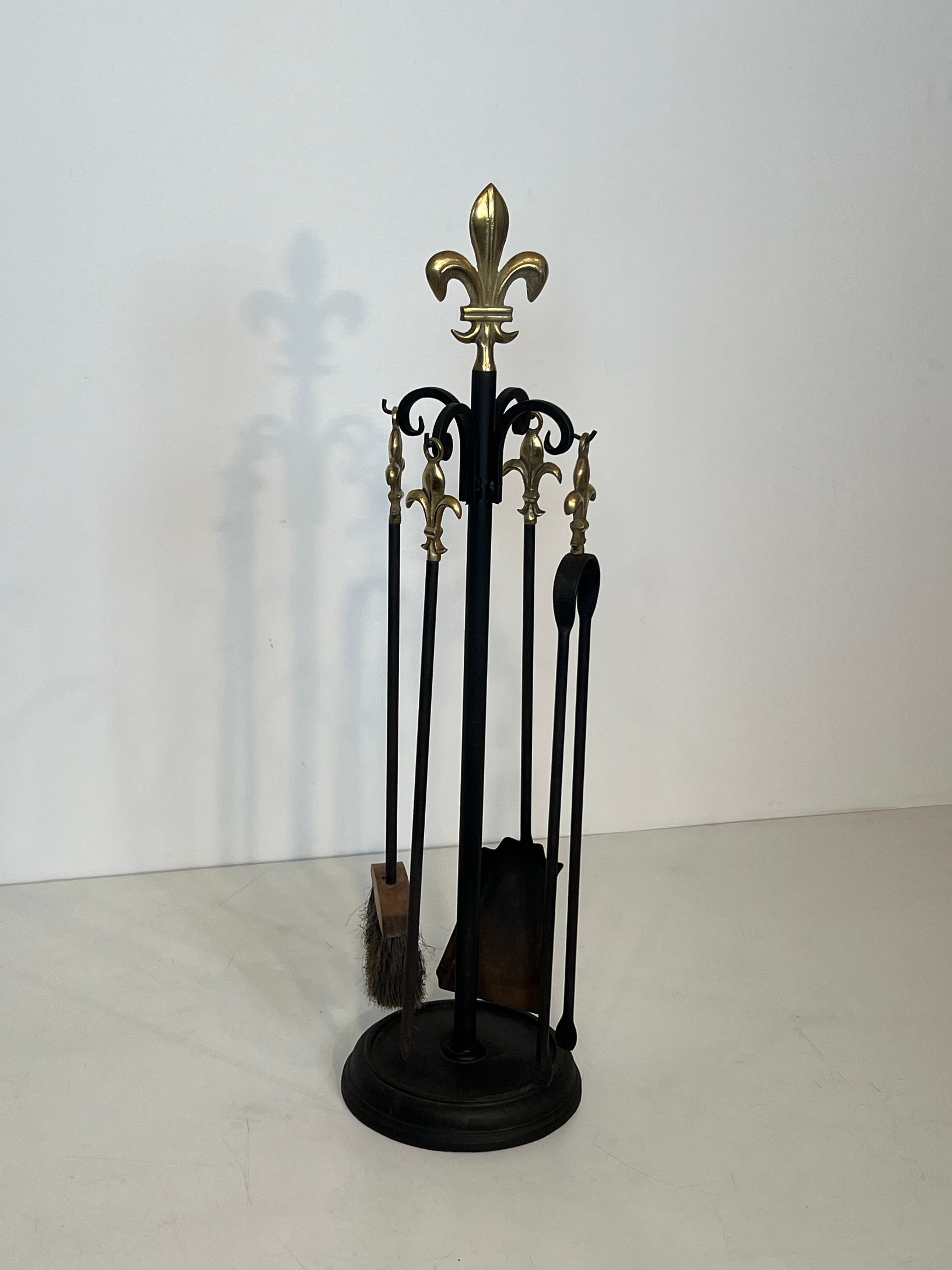 Neoclassical-style fire accessory in black lacquered metal and brass with fleur-de-lis.