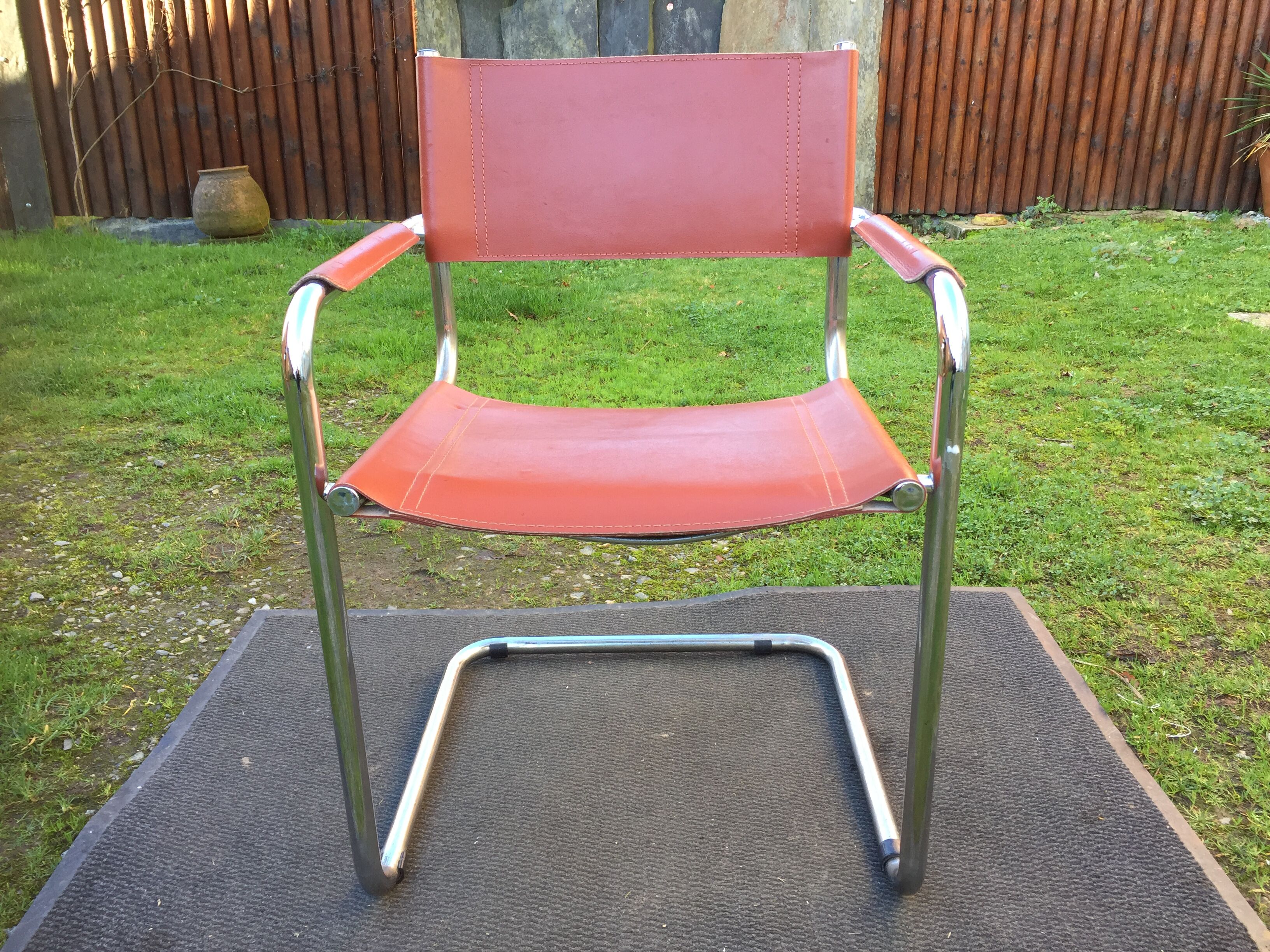 Design armchair with base in chrome tubular steel and seat in brown leather